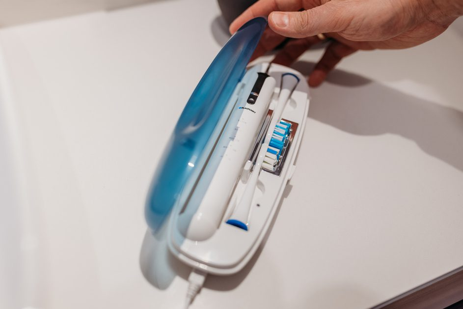 Otwarta biała obudowa z szczoteczką do zębów i akcesoriami na białej powierzchni.