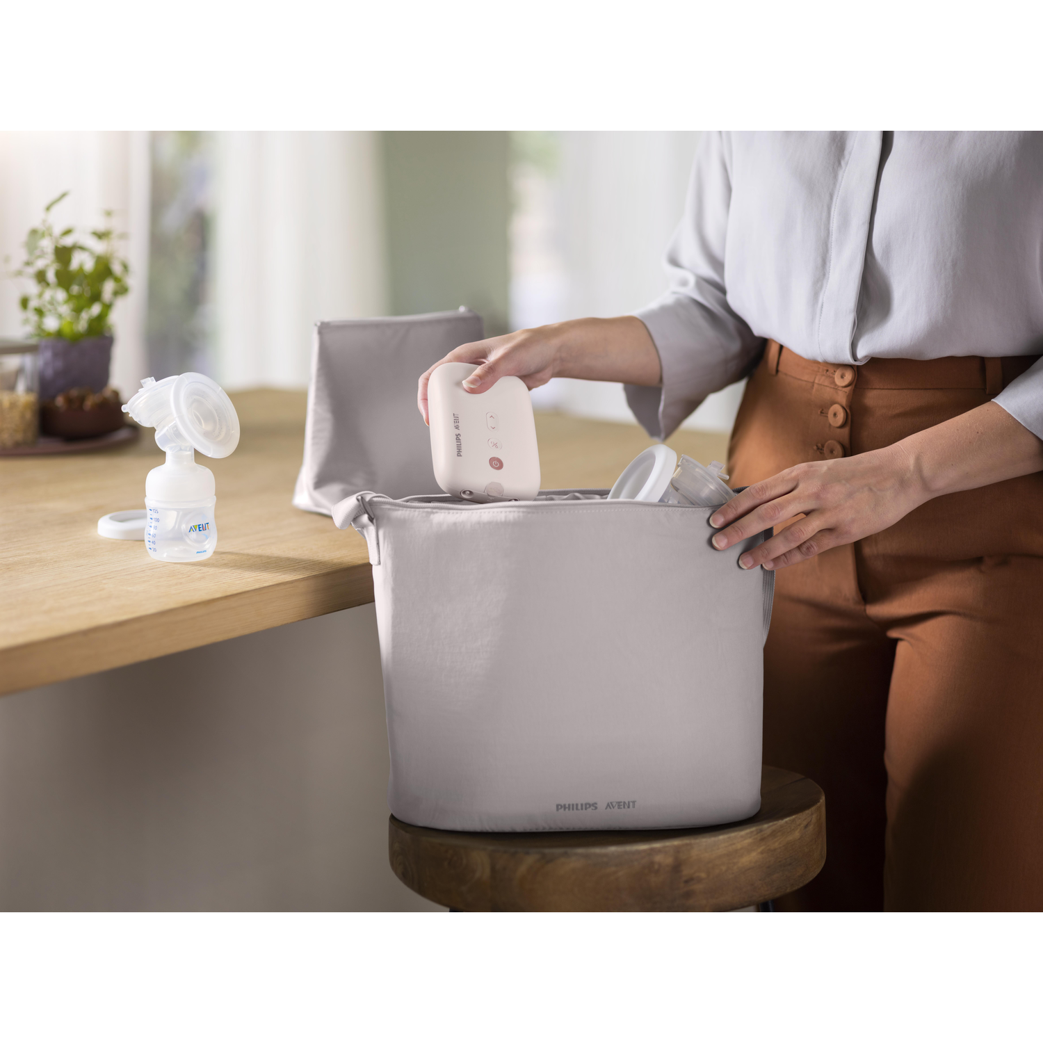 Een persoon die een witte borstkolf in een grijze tas met andere items doet.