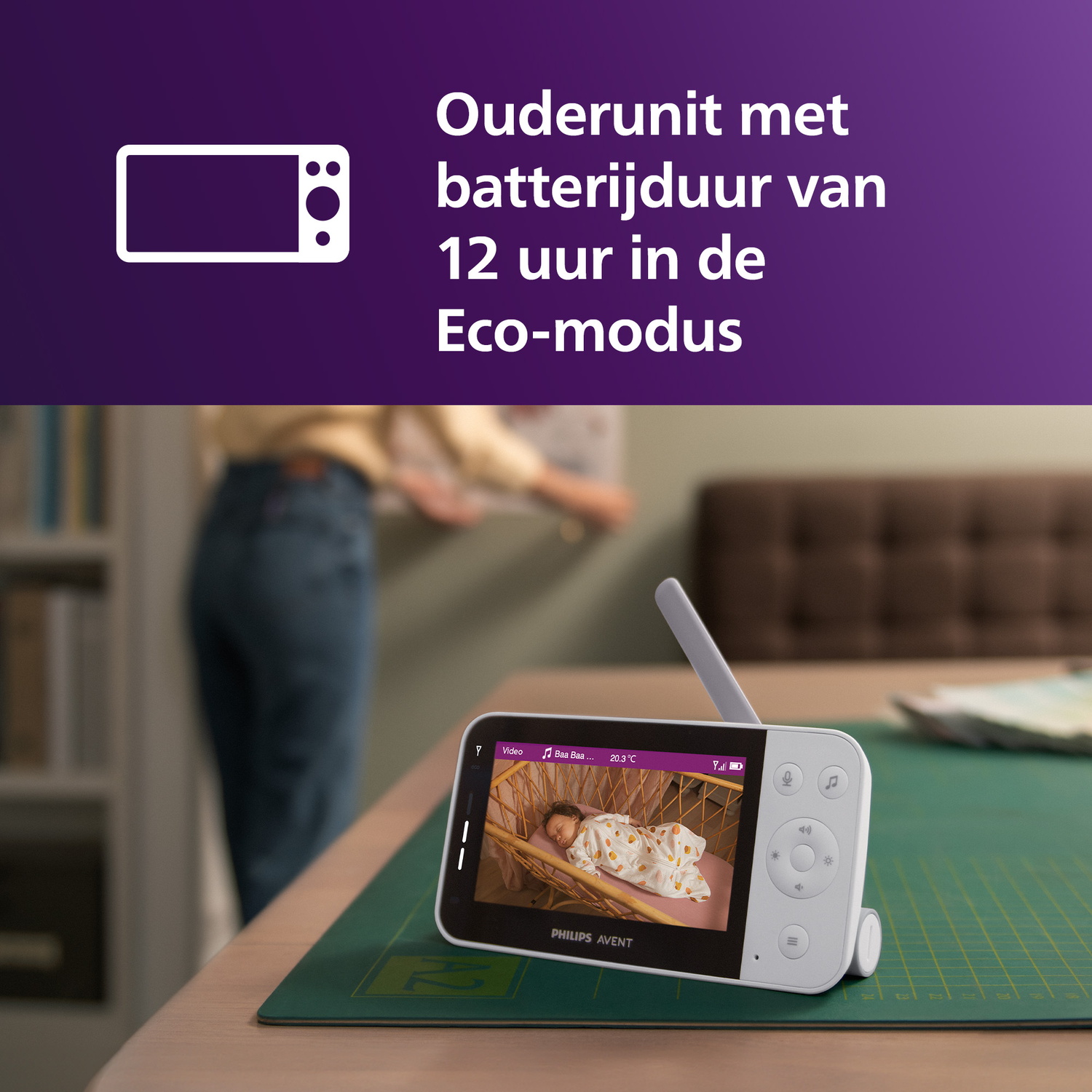 Een persoon bekijkt een babyfoon die een baby toont die in een wieg slaapt.