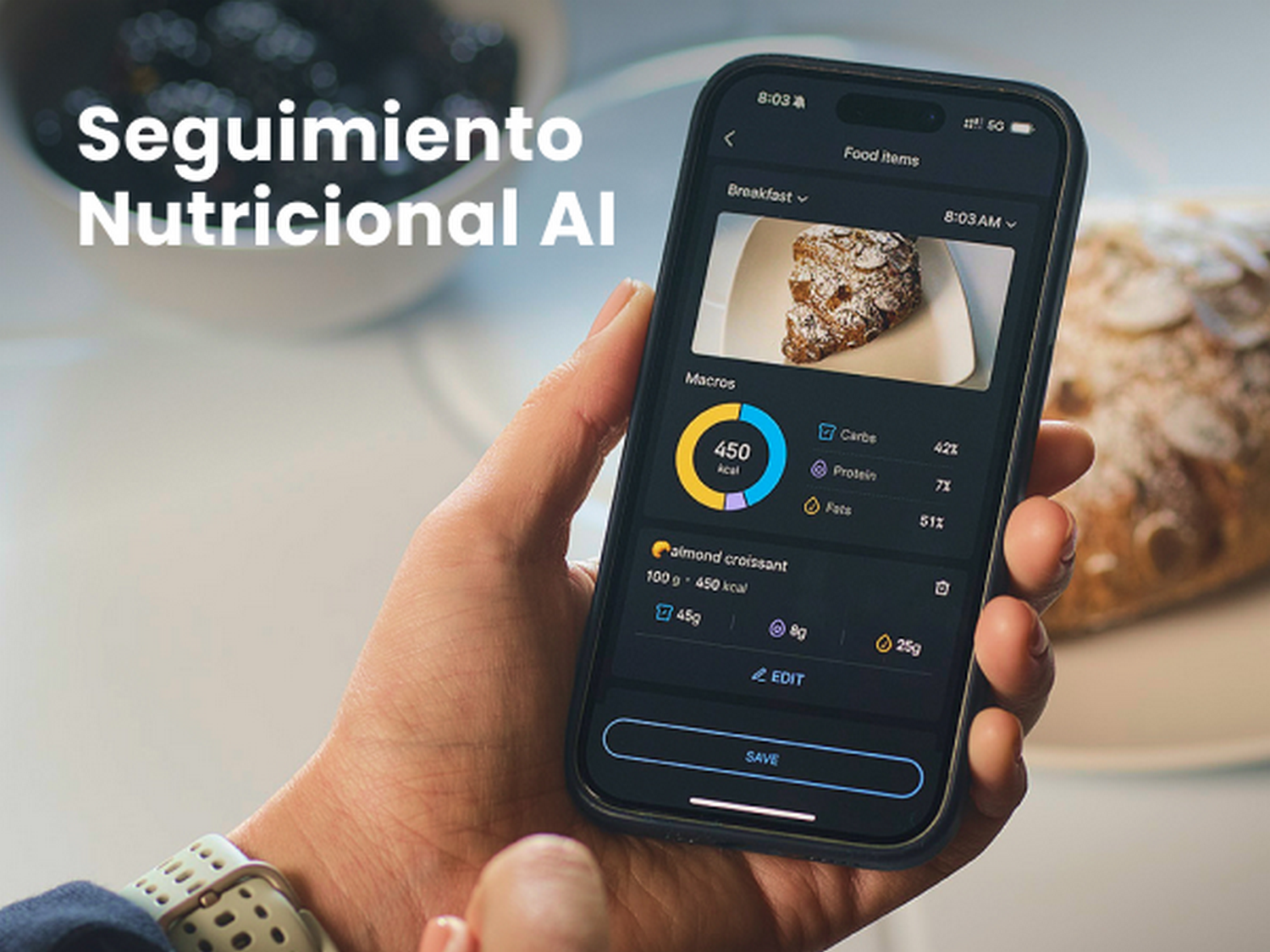 Mano sosteniendo móvil con app de seguimiento nutricional, detalles de croissant.