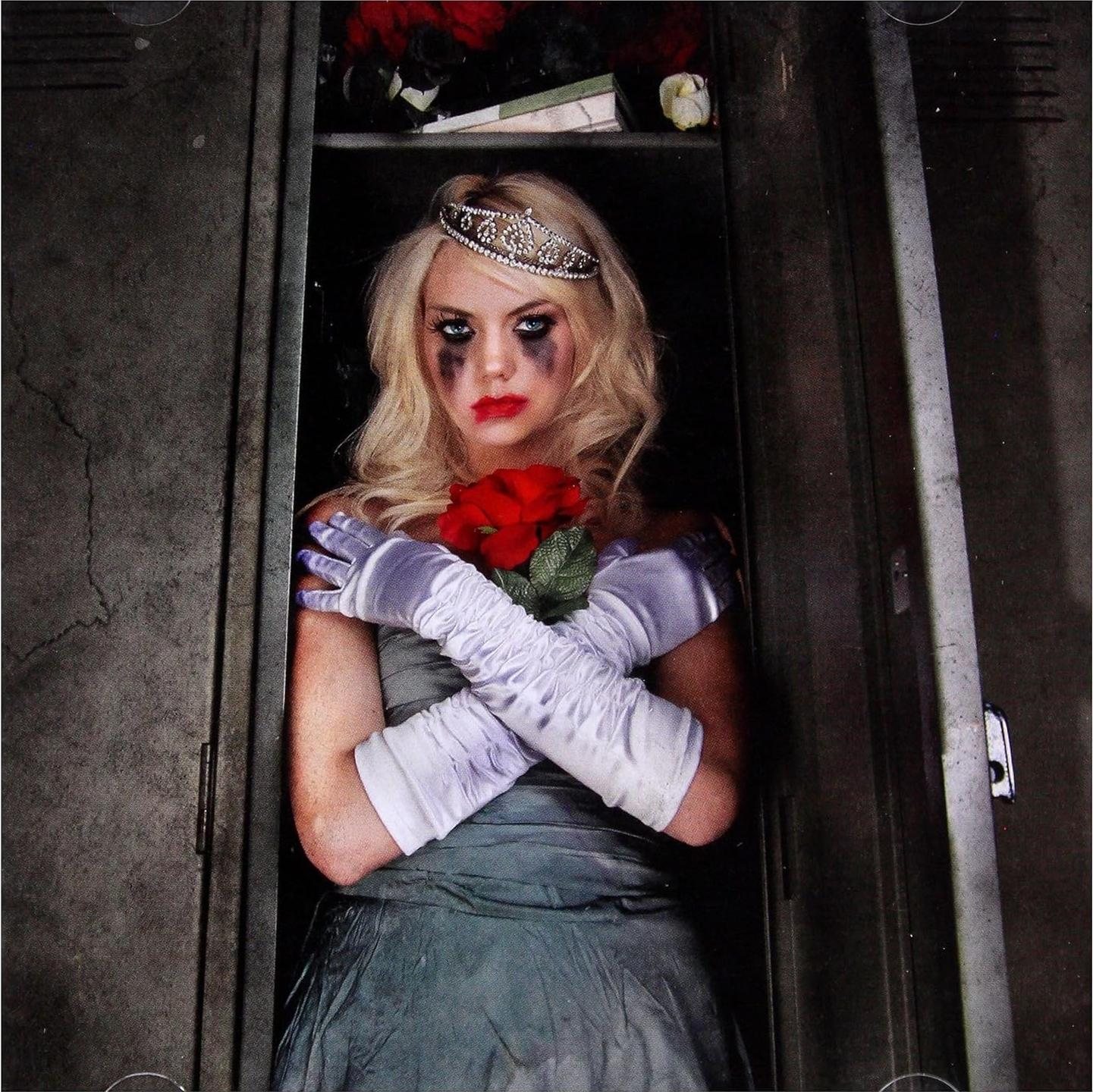 Eine Frau in einem Umkleideraum hält Rosen. Sie hat verschmiertes Make-up und eine Tiara.