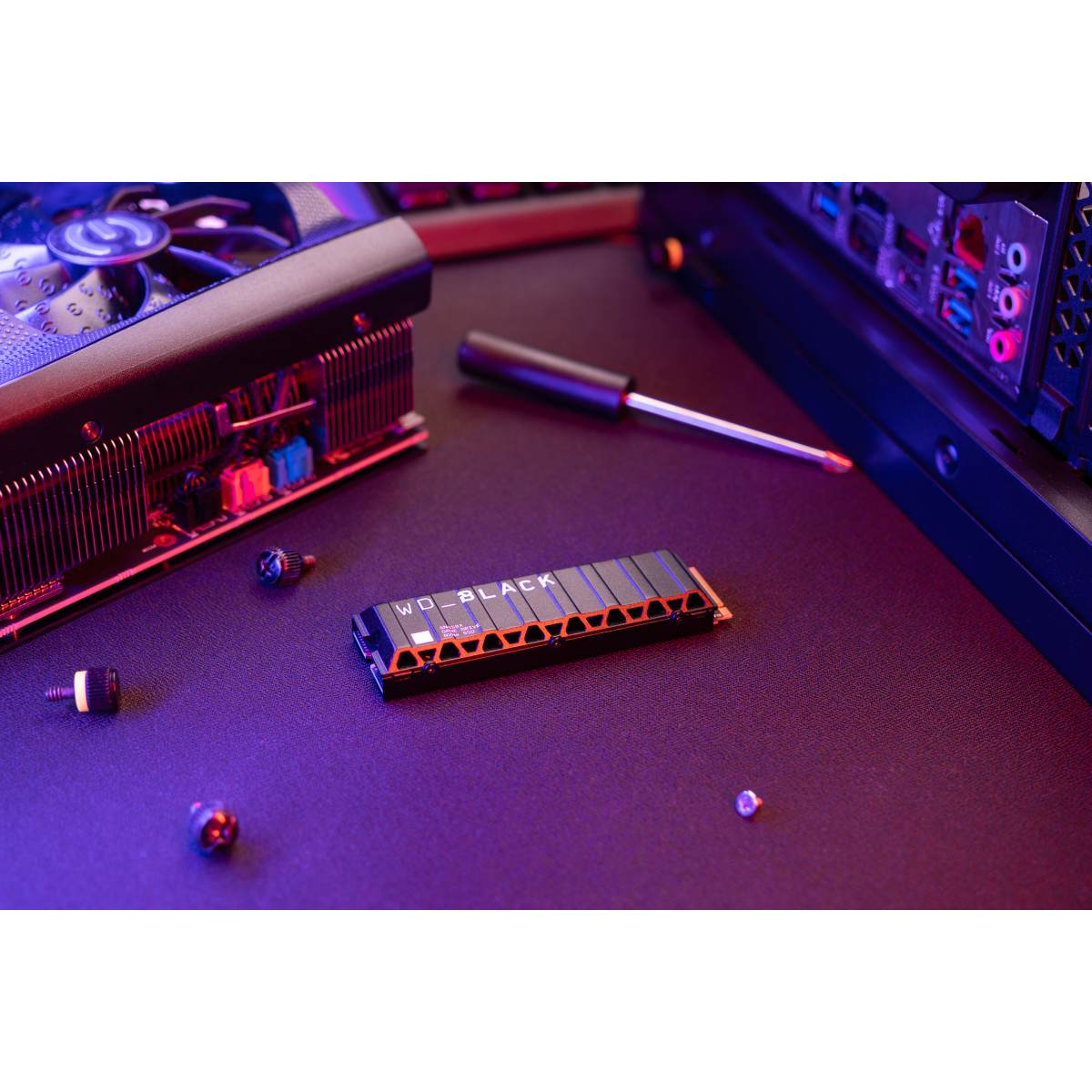 Una SSD, WD_BLACK, con detalles naranjas, tornillos pequeños y un destornillador.