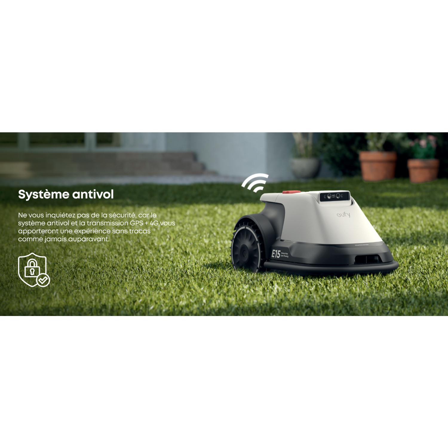 Une tondeuse robot E15 blanche et noire sur de l'herbe verte, avec une plante et une maison.