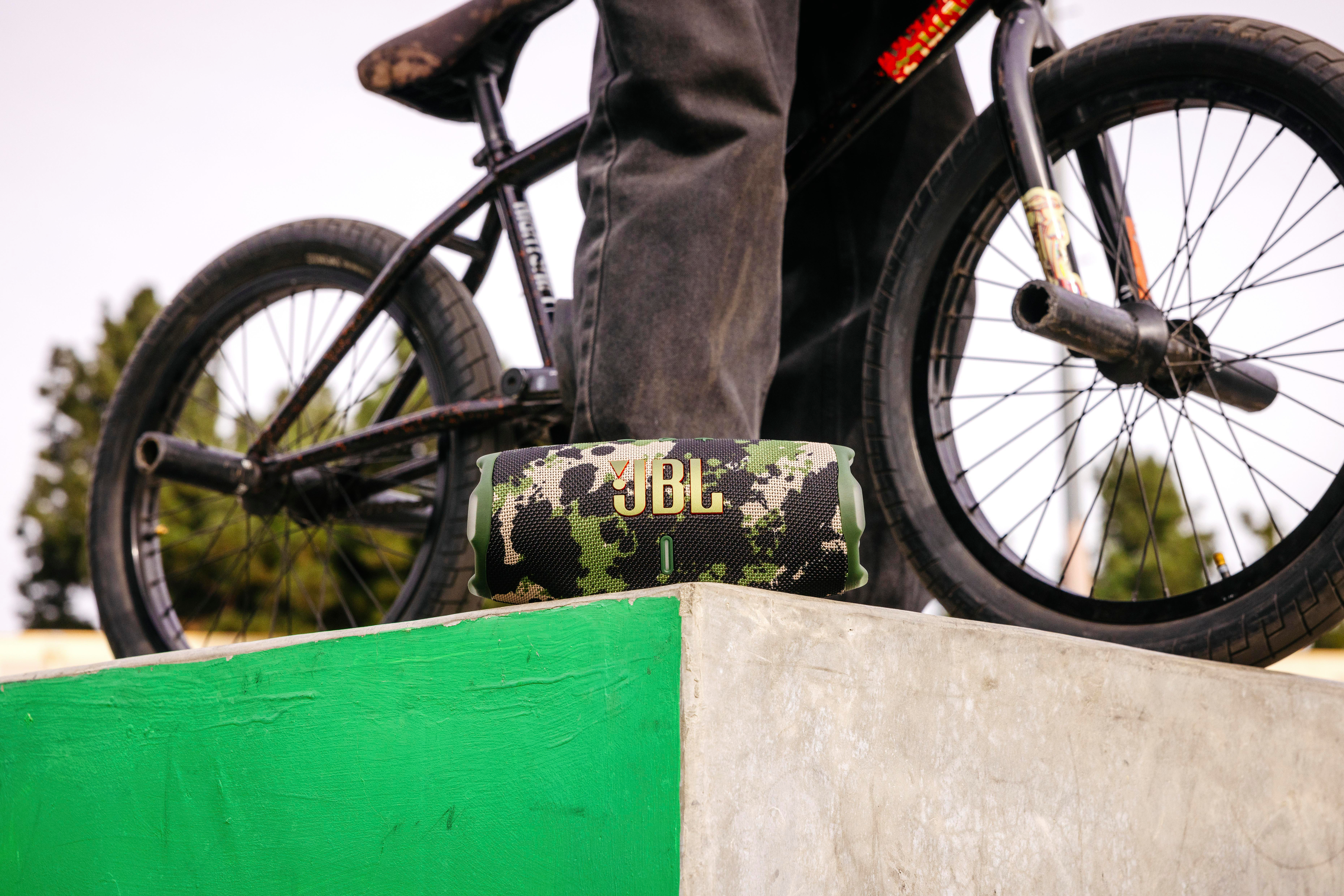 Eine Person steht in der Nähe eines BMX-Fahrrads, und ein tragbarer Lautsprecher steht daneben.