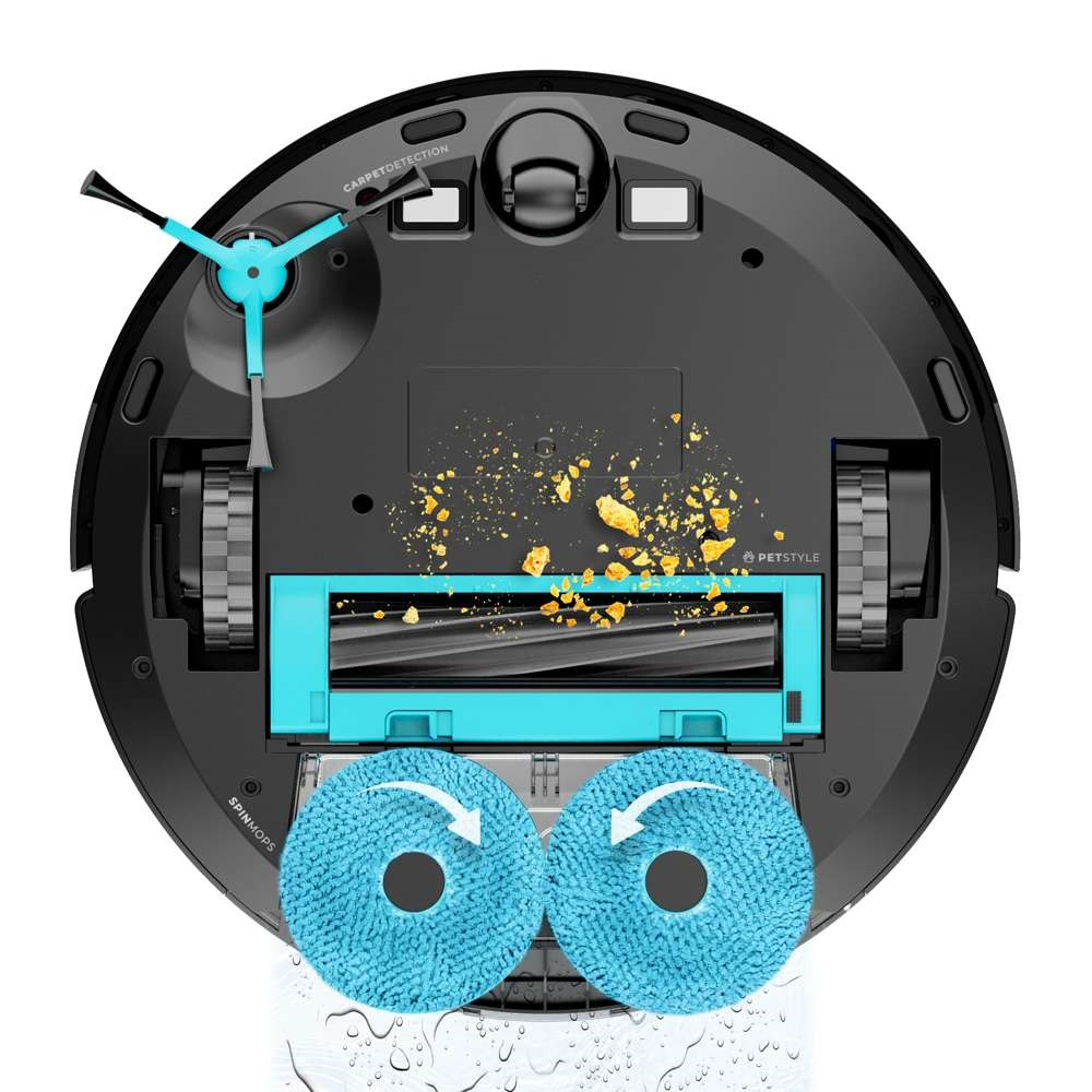 Robot porszívó, alsó része látható, kefékkel és tisztítópárnákkal. Sárga törmelék.