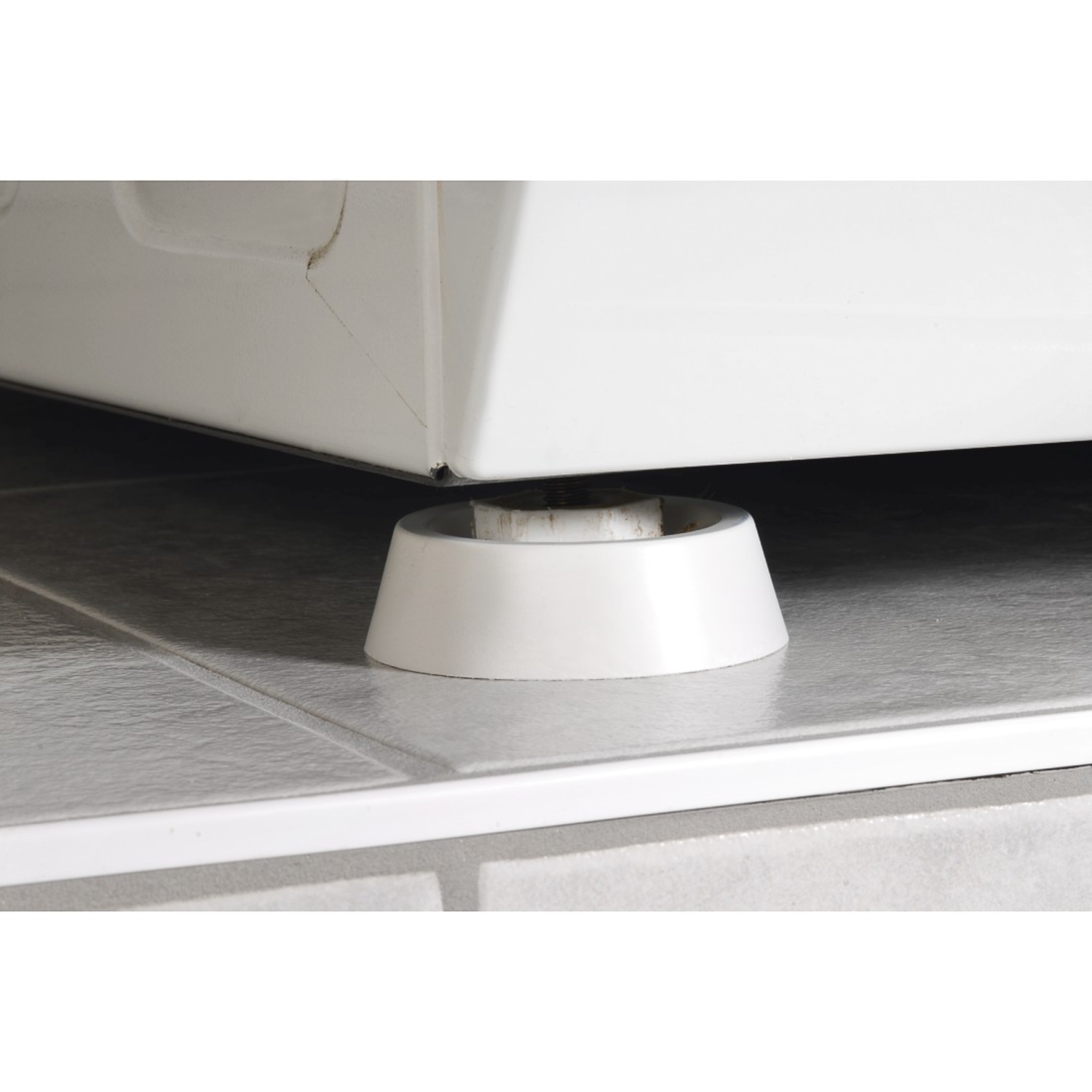 White appliance on white tile floor, supported by a white, conical leg, close-up view.