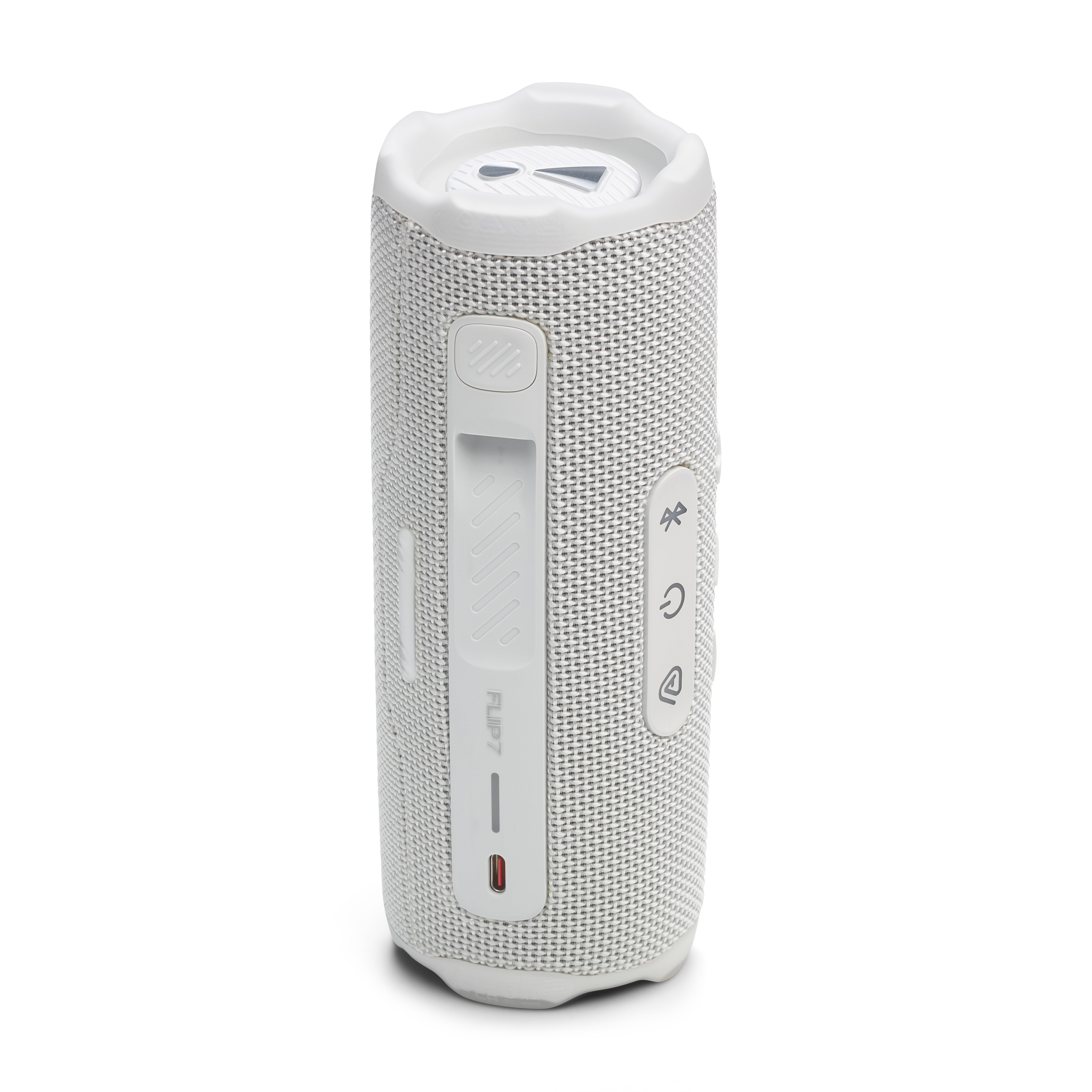 Ein weißer JBL Flip 7 Lautsprecher. Der Lautsprecher hat Knöpfe und einen Ladeanschluss. Es ist auf weißem Hintergrund.