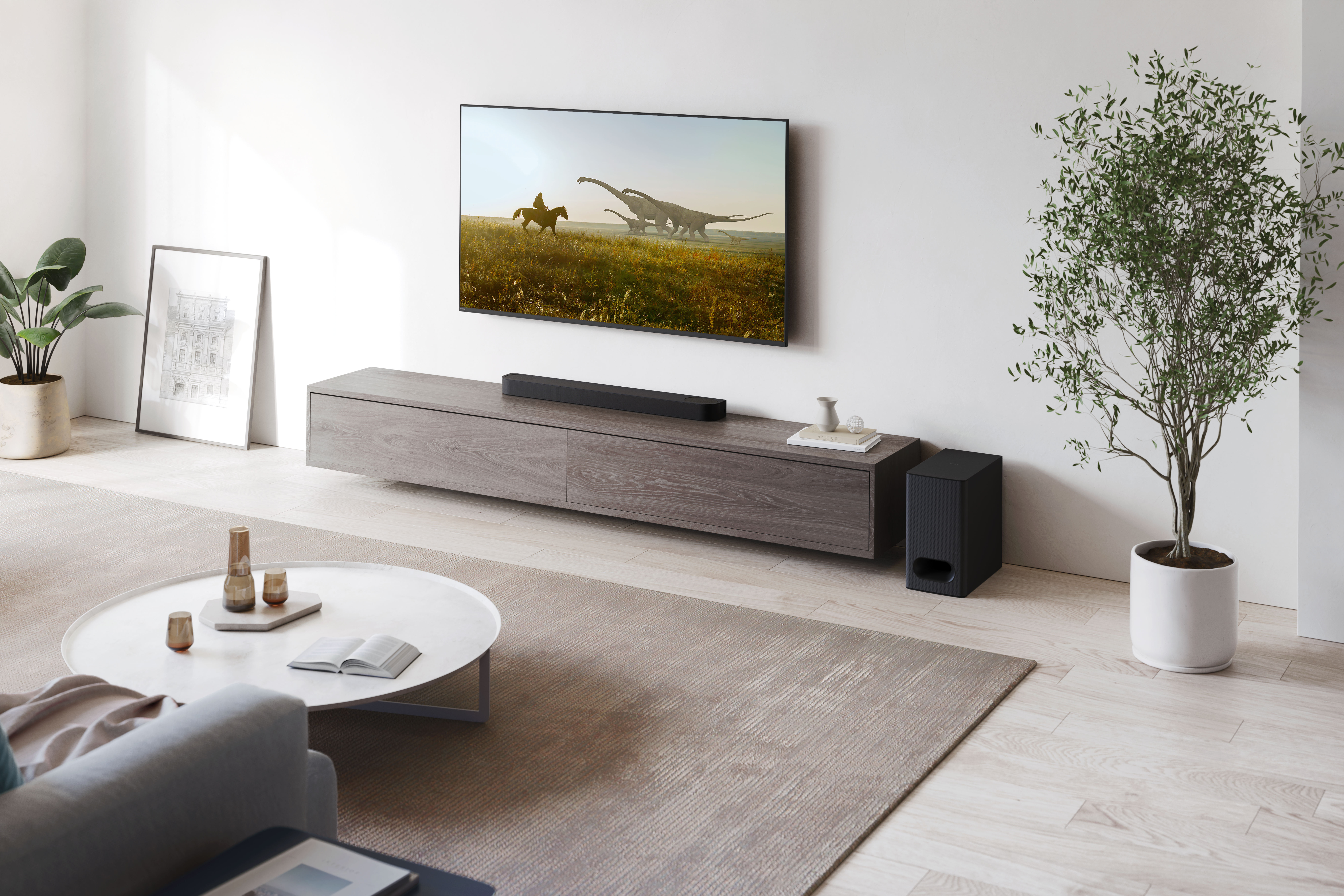 Wohnzimmer mit TV an der Wand, Soundbar, Subwoofer und rundem Couchtisch. Modernes Design.