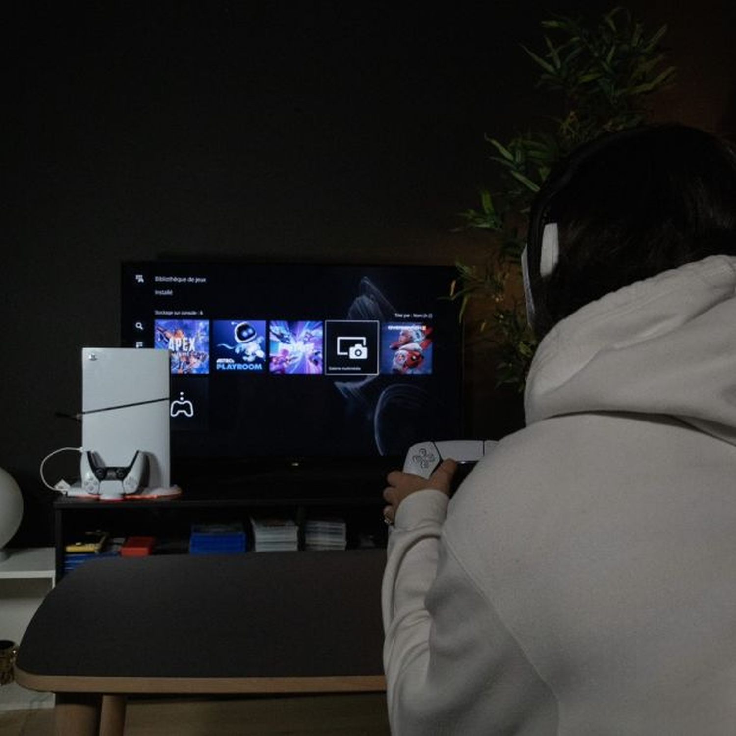 Une personne joue à un jeu vidéo. Elle porte un casque et tient une manette.