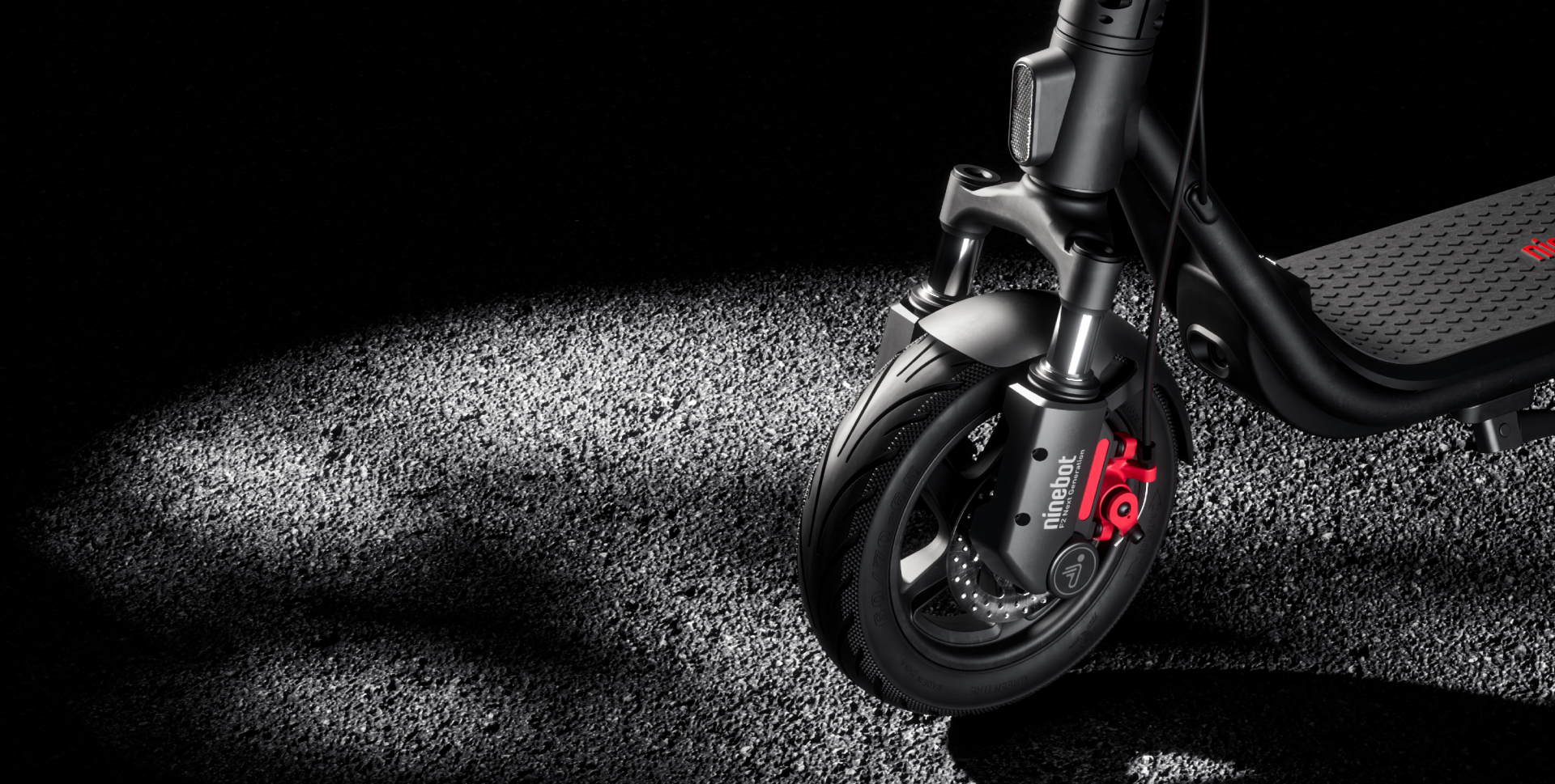 Czarna hulajnoga z czerwonymi hamulcami, na teksturowanej powierzchni.
