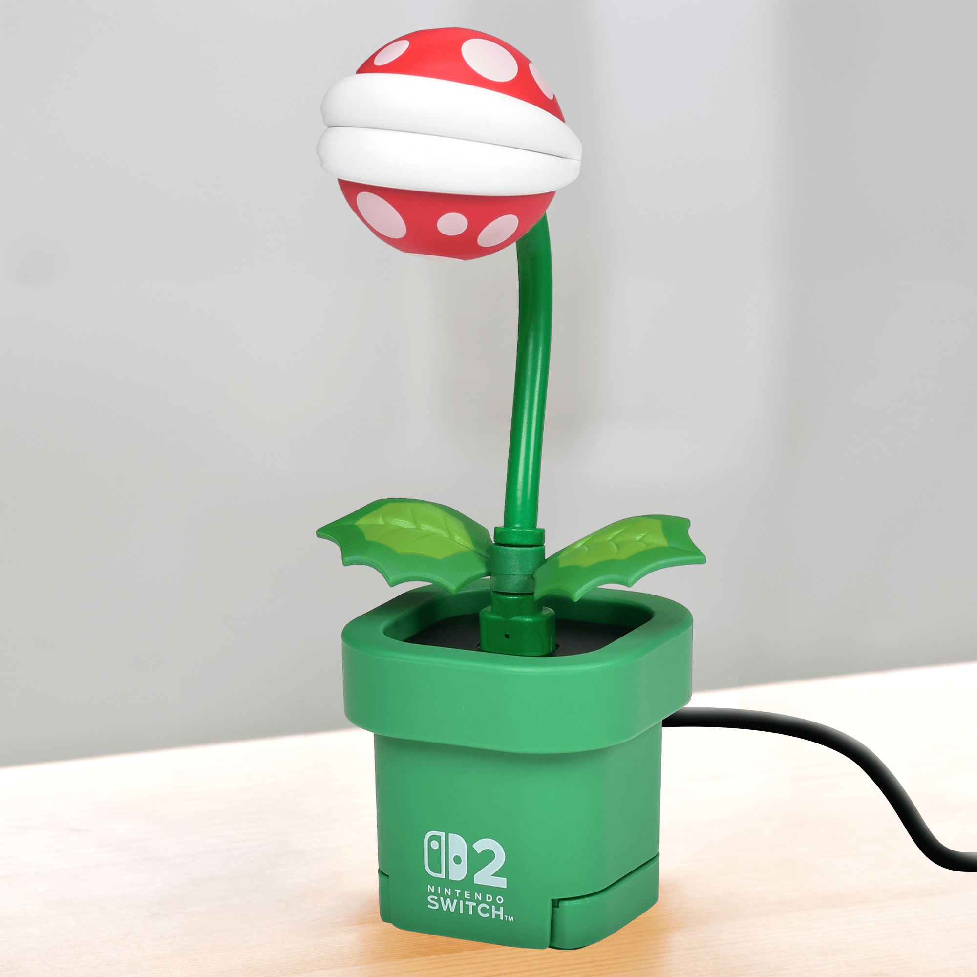 Una lampada Pianta Piranha di Super Mario in un vaso verde su una superficie di legno.
