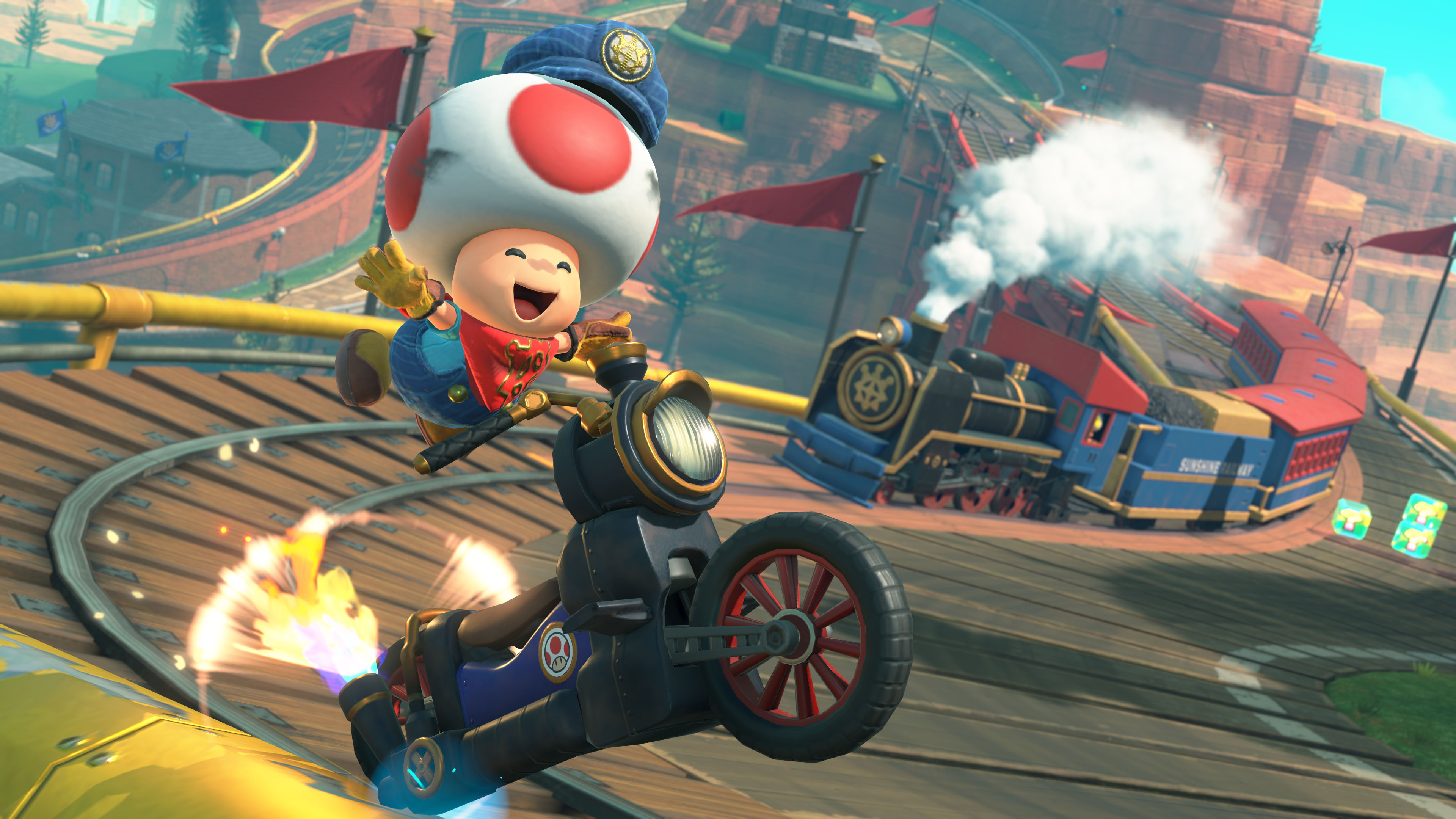 Toad fährt Motorrad, Mario Kart, auf einer Strecke mit Zug und Flaggen.
