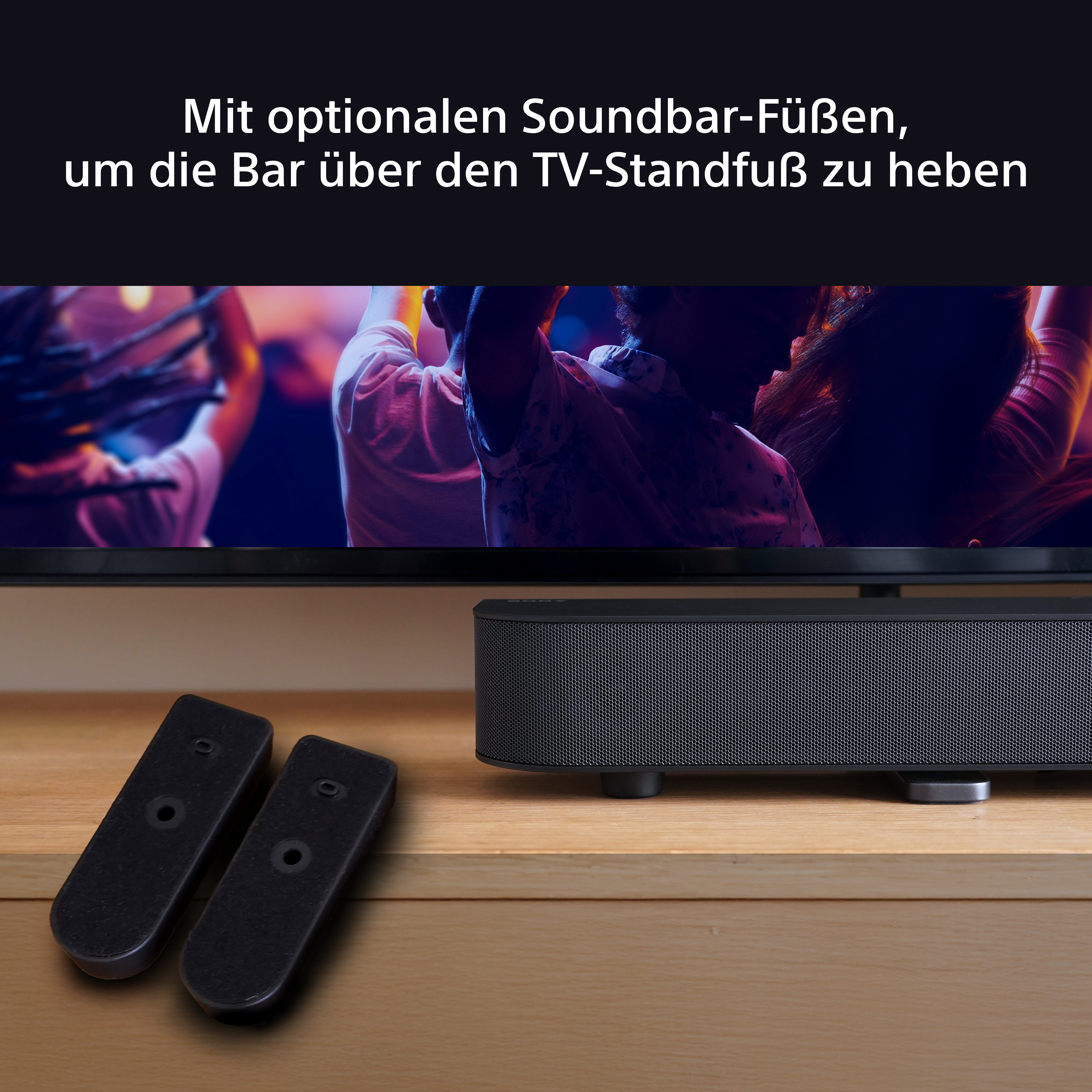 Soundbar mit zwei schwarzen Fernbedienungen. Der Fernseher ist an. Holztisch.