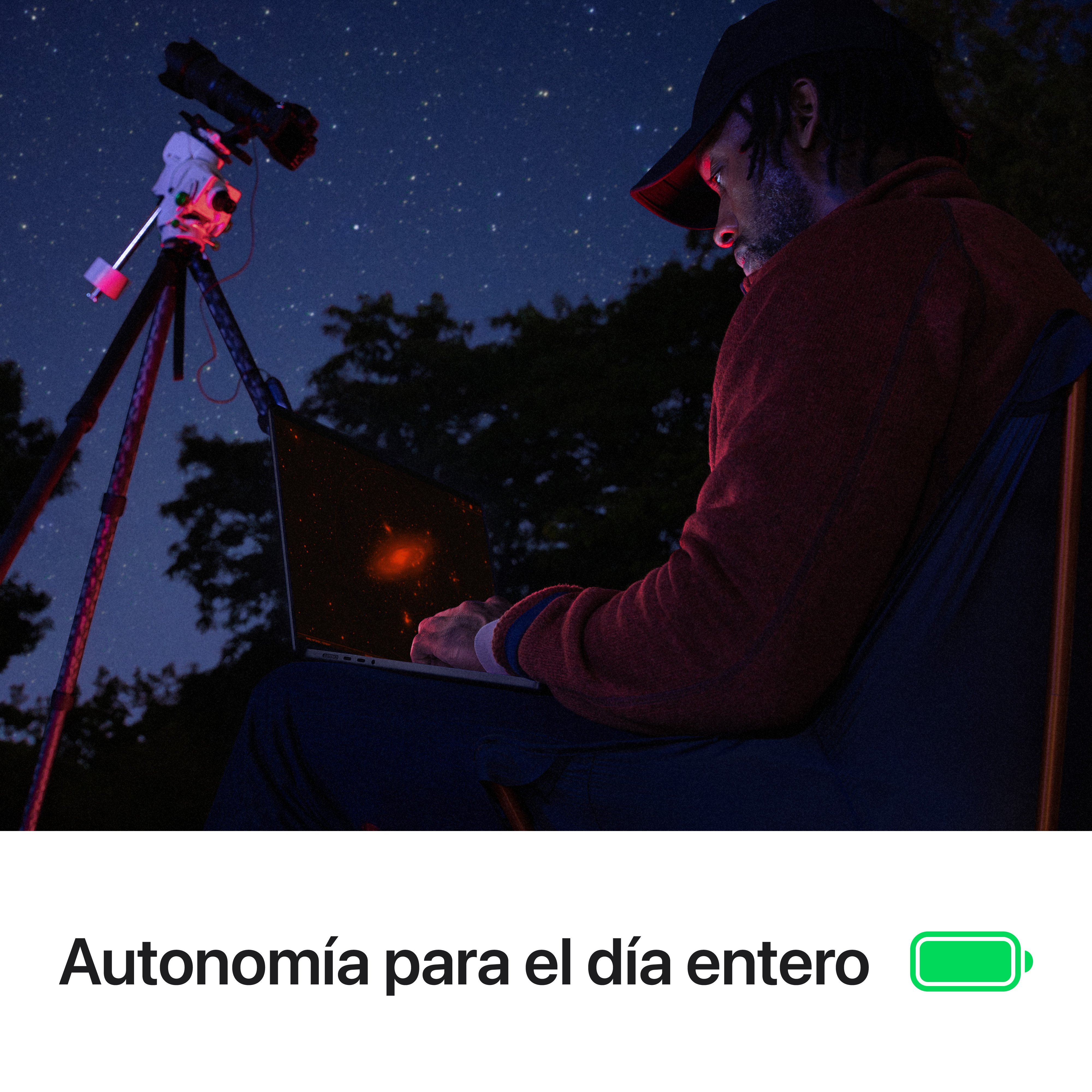 Hombre usando una laptop por la noche cerca de un telescopio.