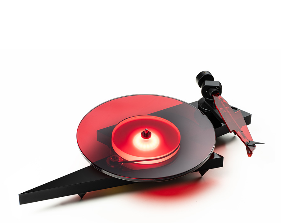 Schwarzer Plattenspieler mit roter, transparenter Schallplatte. Weißer Hintergrund, modernes Design.