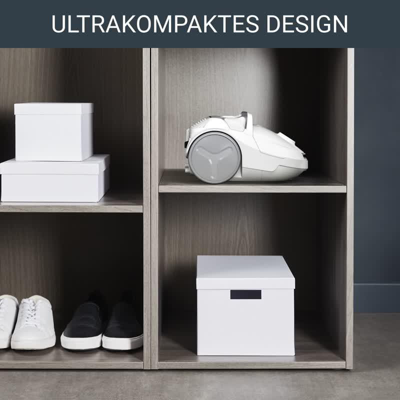 Ein grauer Schrank mit weißen Boxen und einem weißen Staubsauger.