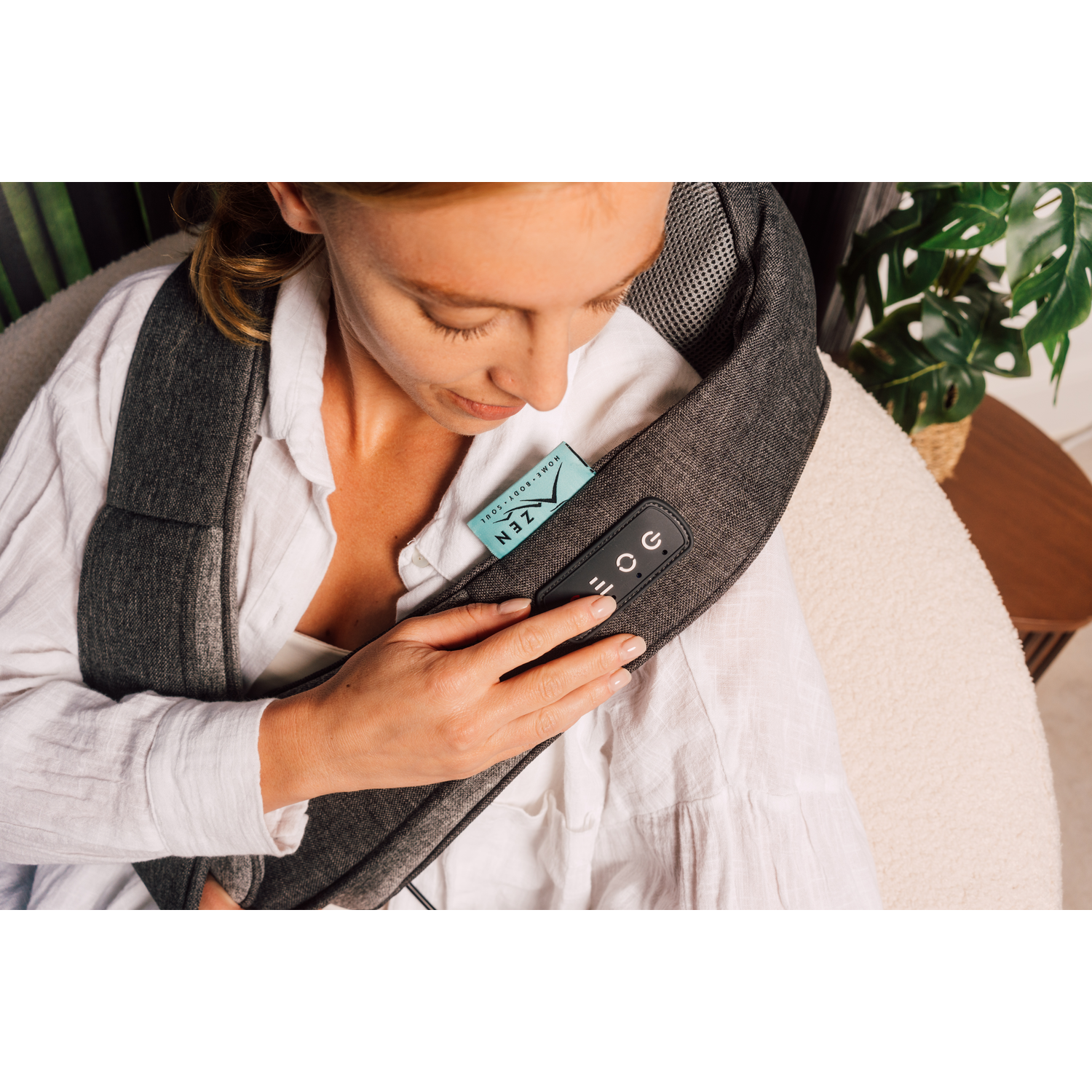 A woman wearing a neck massager with a remote control in her hand.