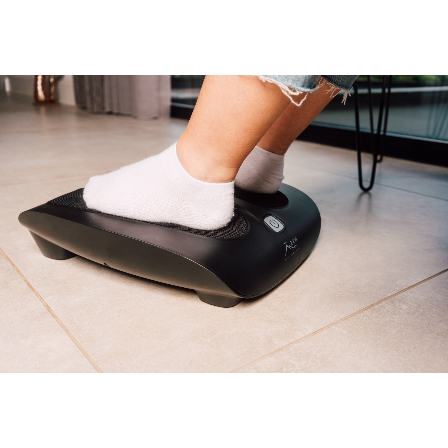 Person's foot in green foot spa, black sofa in background.