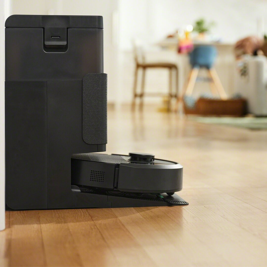 Robot odkurzający i jego stacja ładująca. Podłoga jest widoczna.