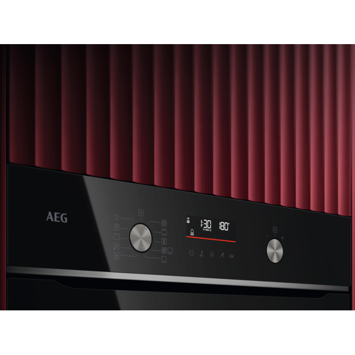 Primer plano del panel de control de un horno negro, mostrando botones, una pantalla y el logotipo de AEG.