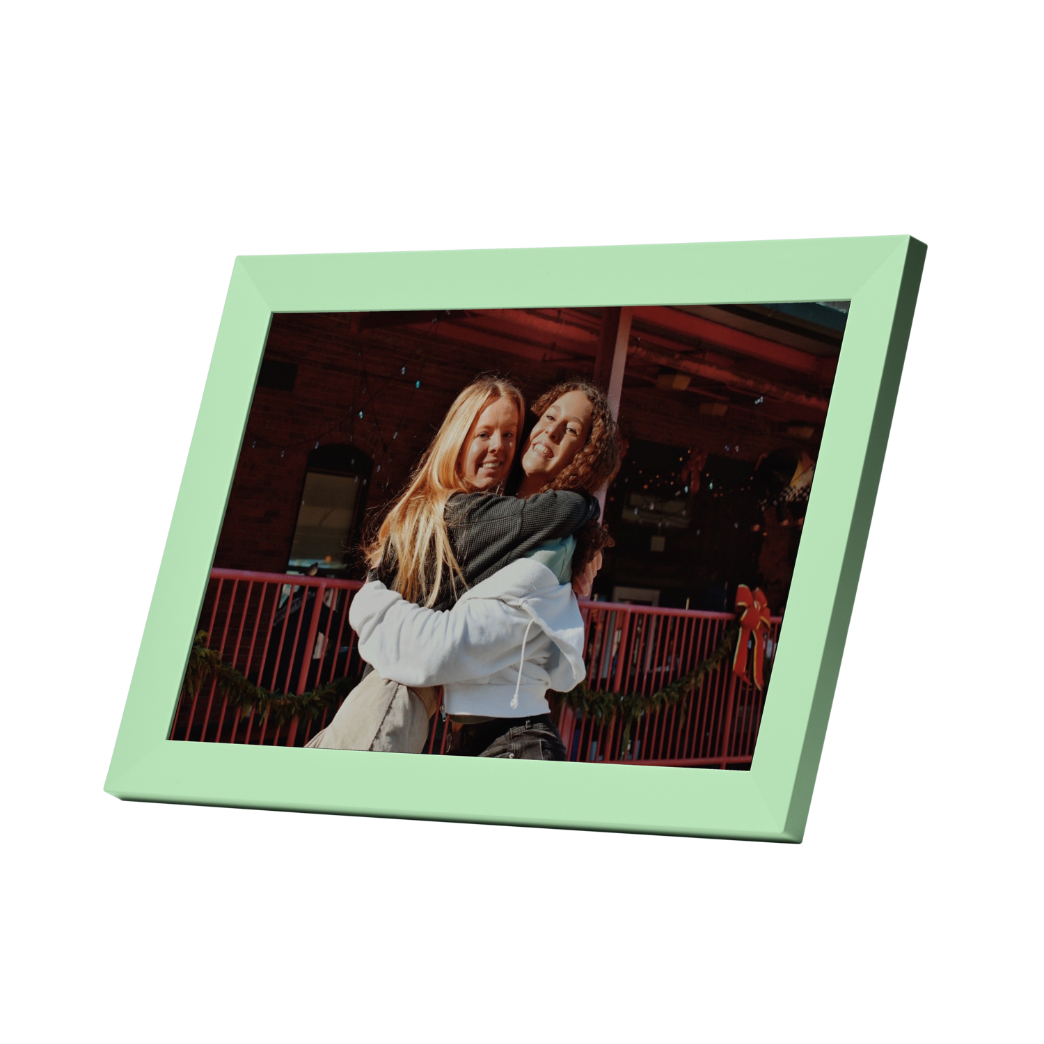 Two women hugging in front of a red building.