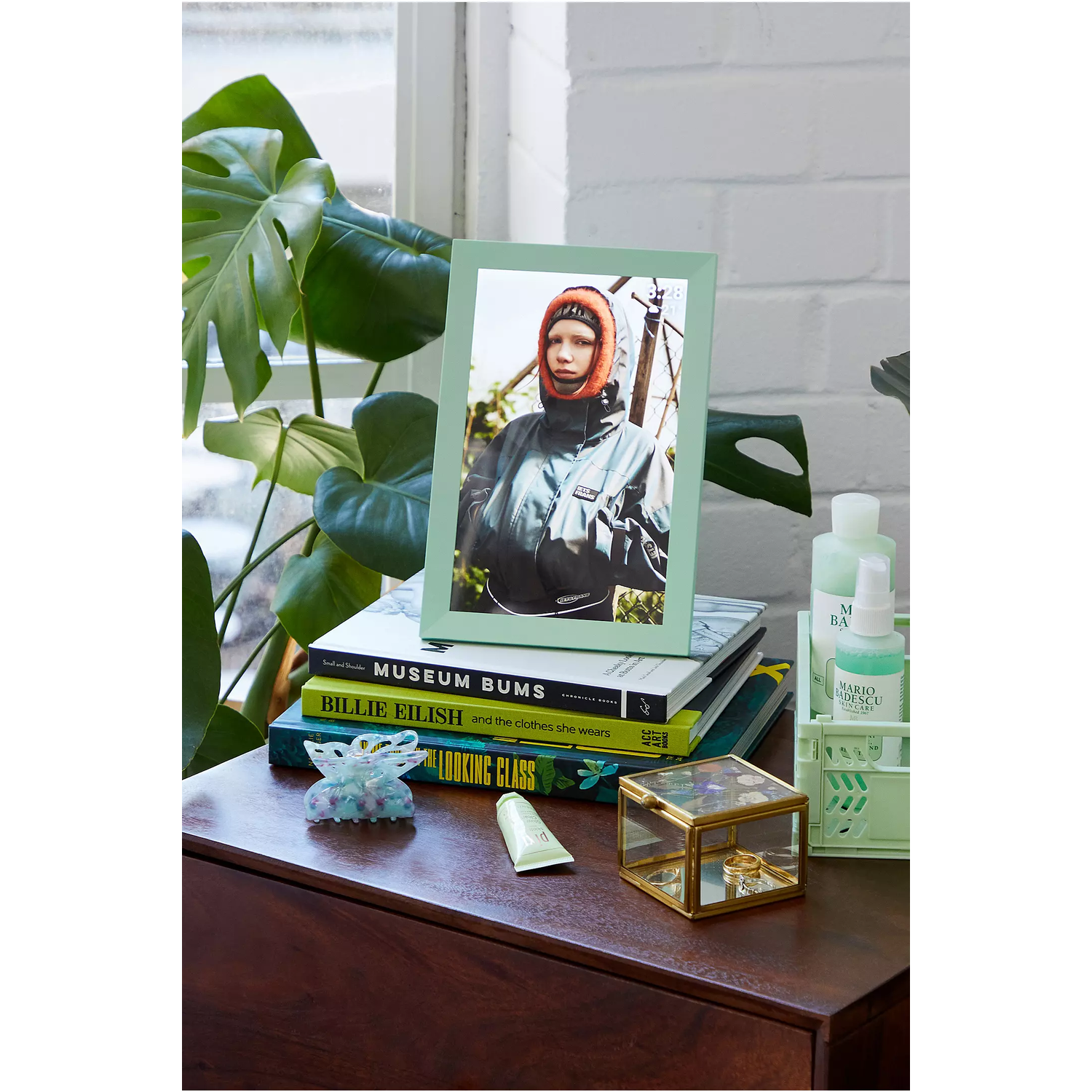 A framed photo on a table with books, a jewelry box, and beauty products.
