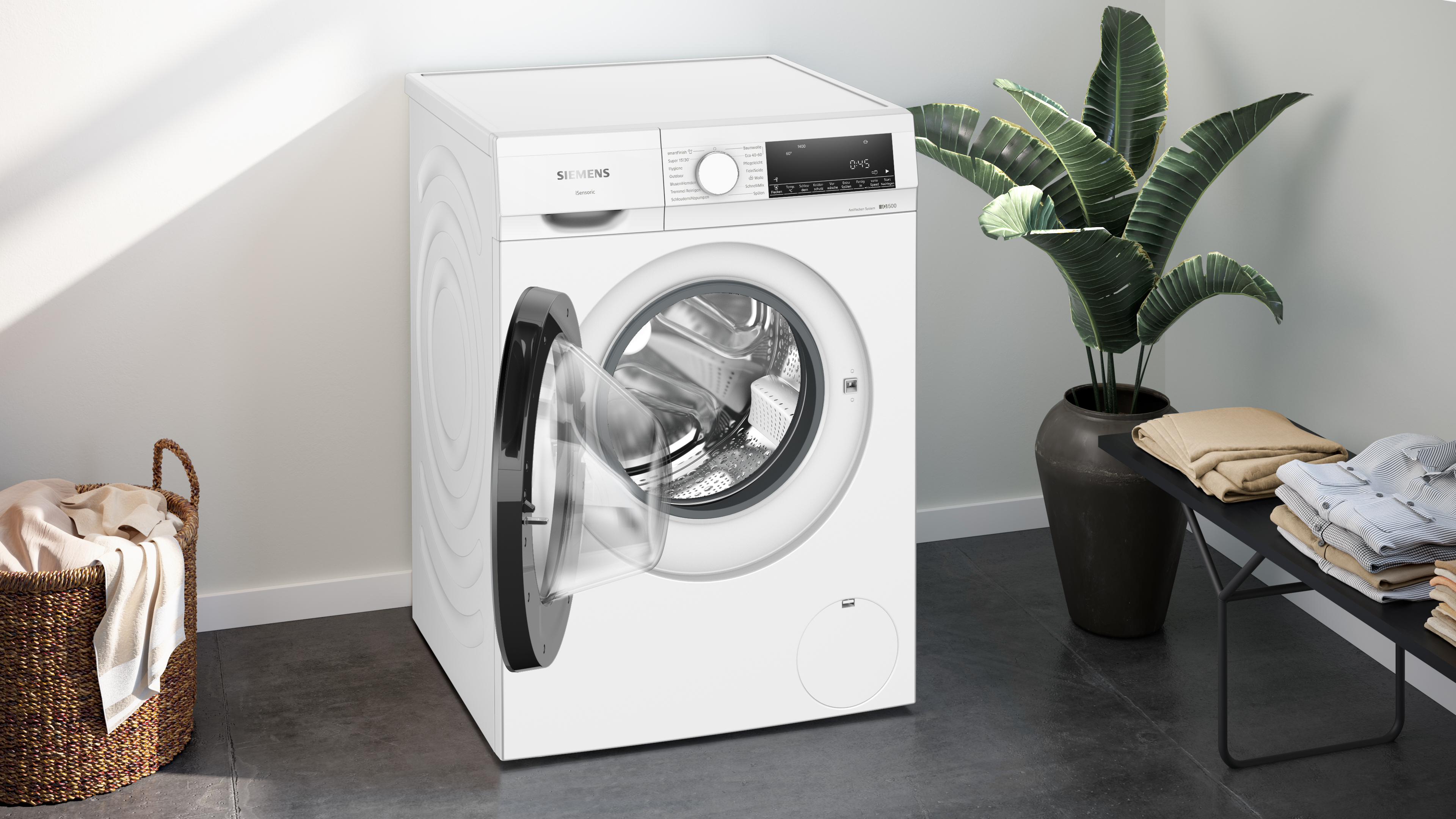 Weiße Siemens Waschmaschine mit offener Tür, Wäschekorb und Pflanzen rechts.