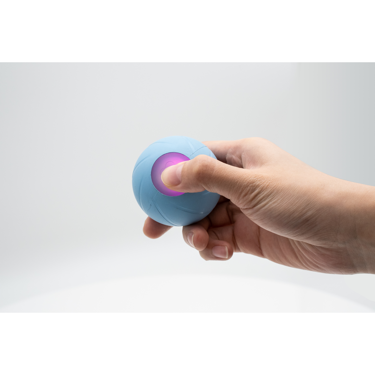 A hand holding a blue ball with a glowing purple light in the center.