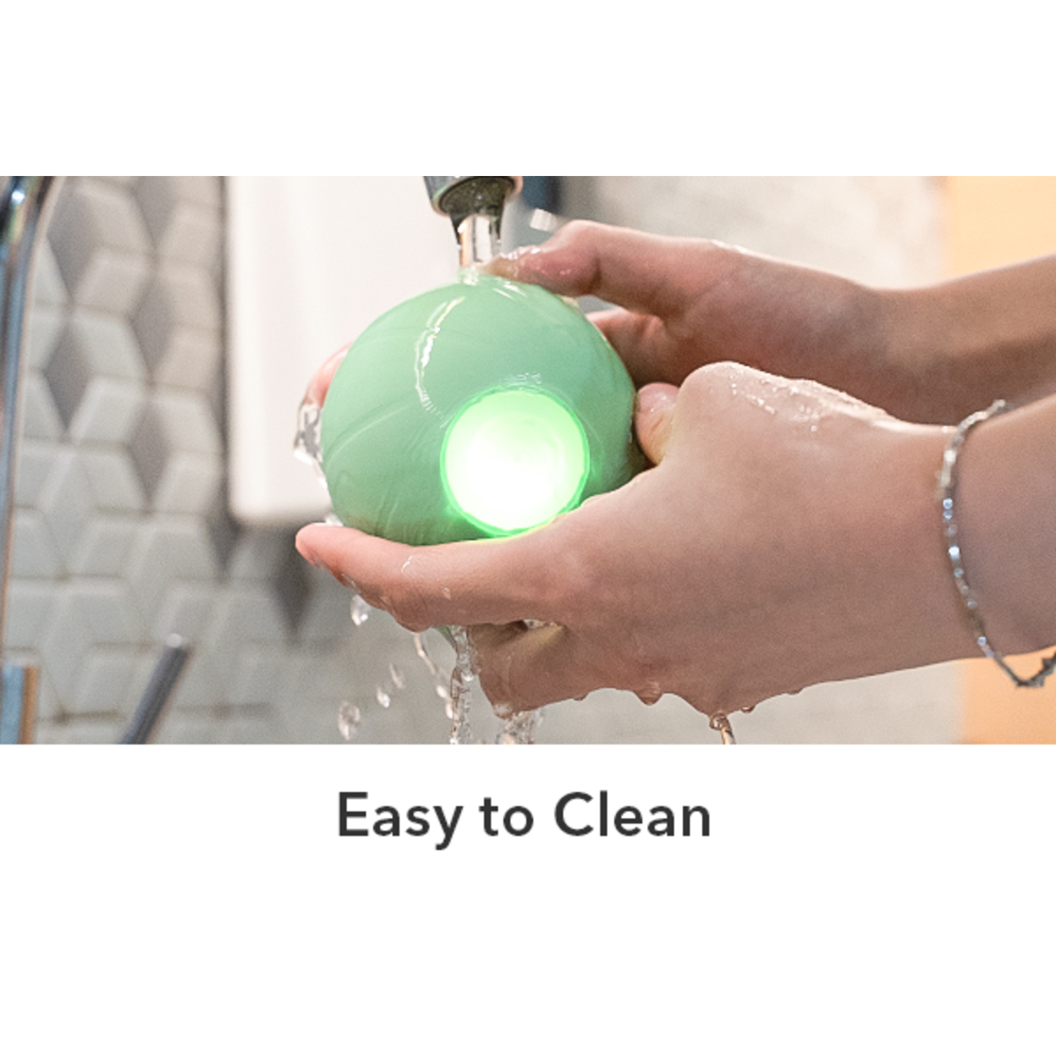 Hands holding a green sphere under running water, with a bright green light.