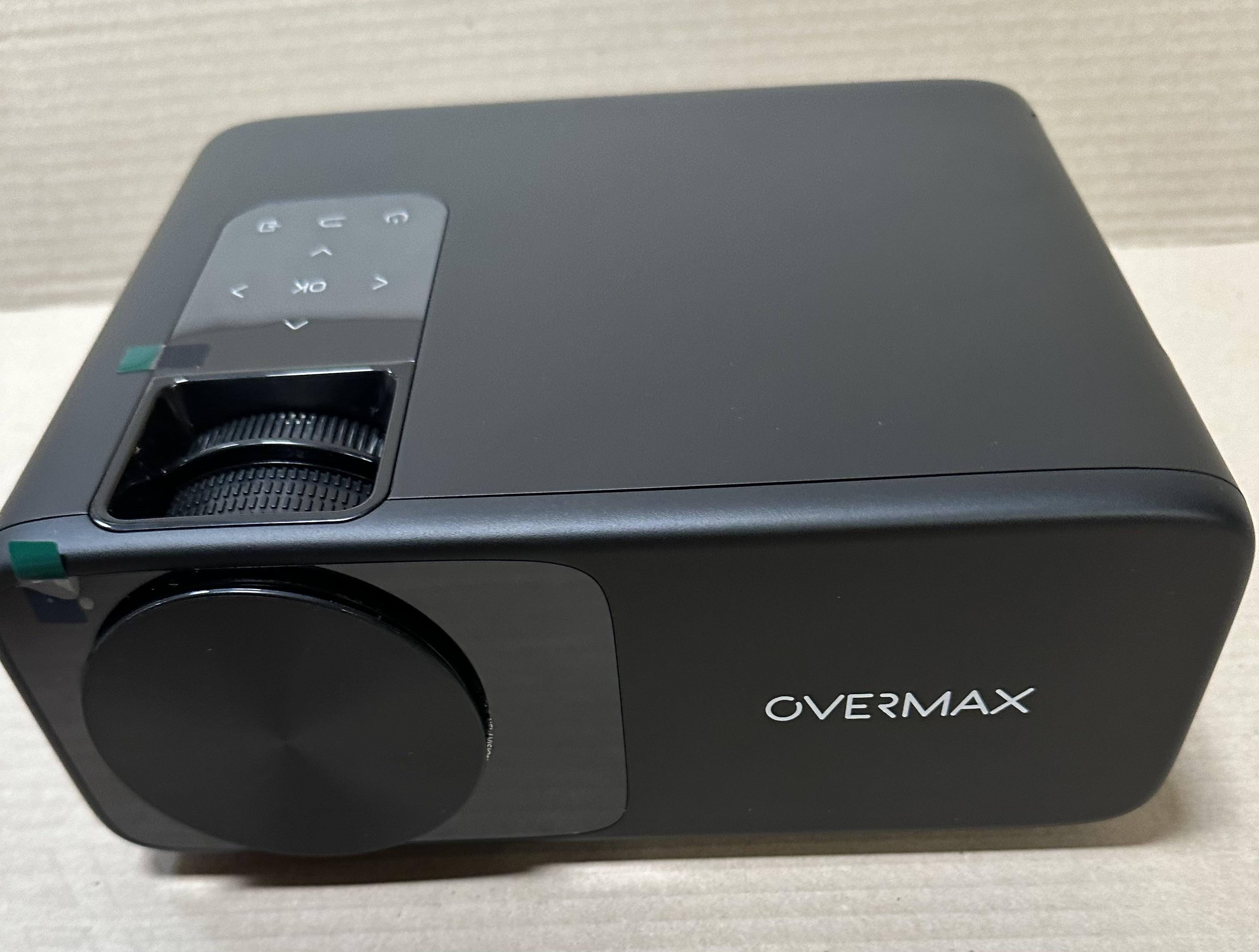 Czarny projektor z przyciskami sterowania i napisem OVERMAX z boku.