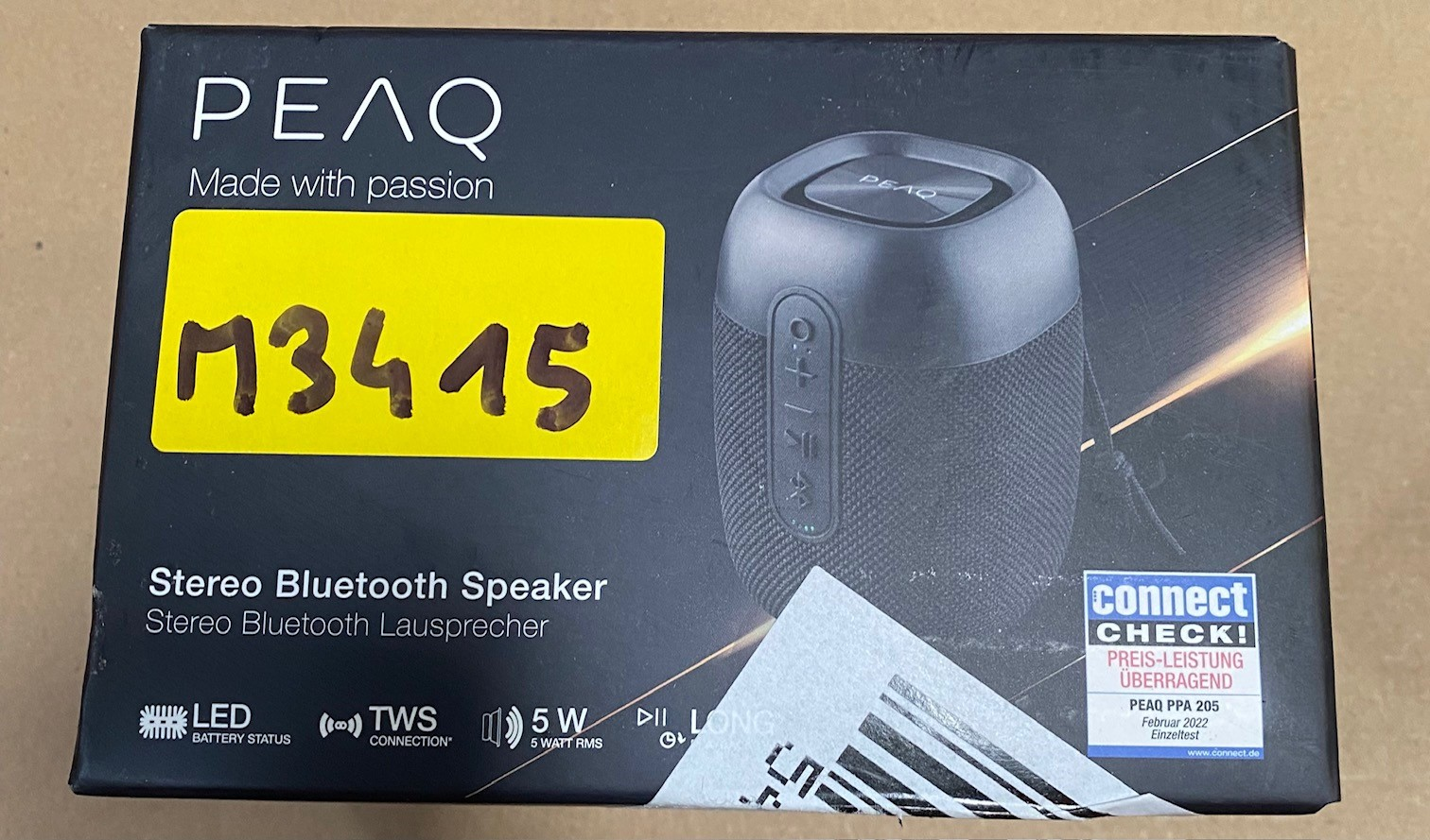 Czarny głośnik stereo bluetooth z żółtą naklejką i tekstem na nim.