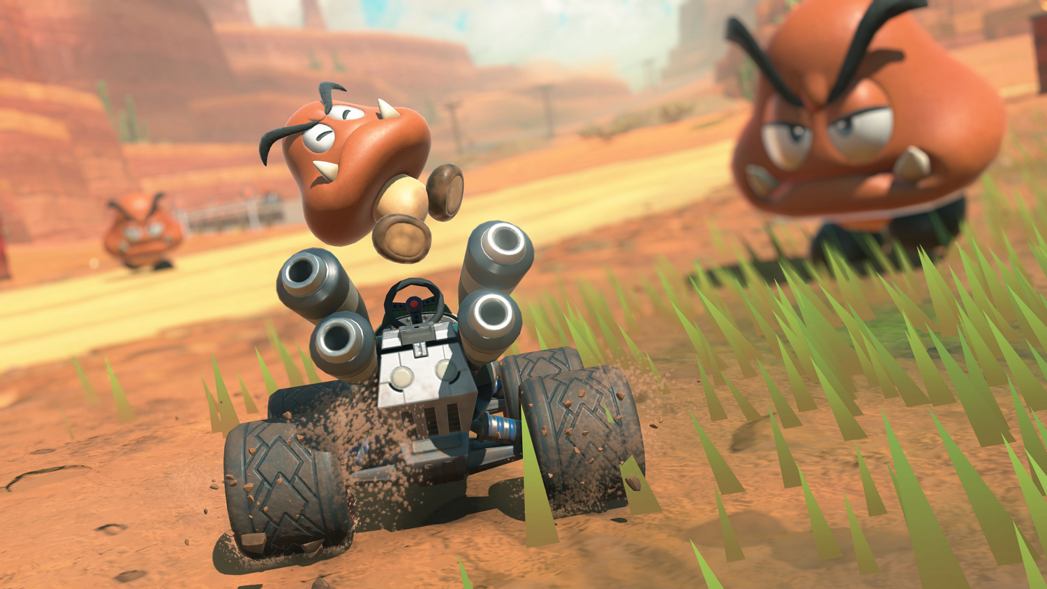 Una carrera de karts en una pista desértica. Un Goomba salta sobre el kart. Hay dos Goombas más en el fondo.