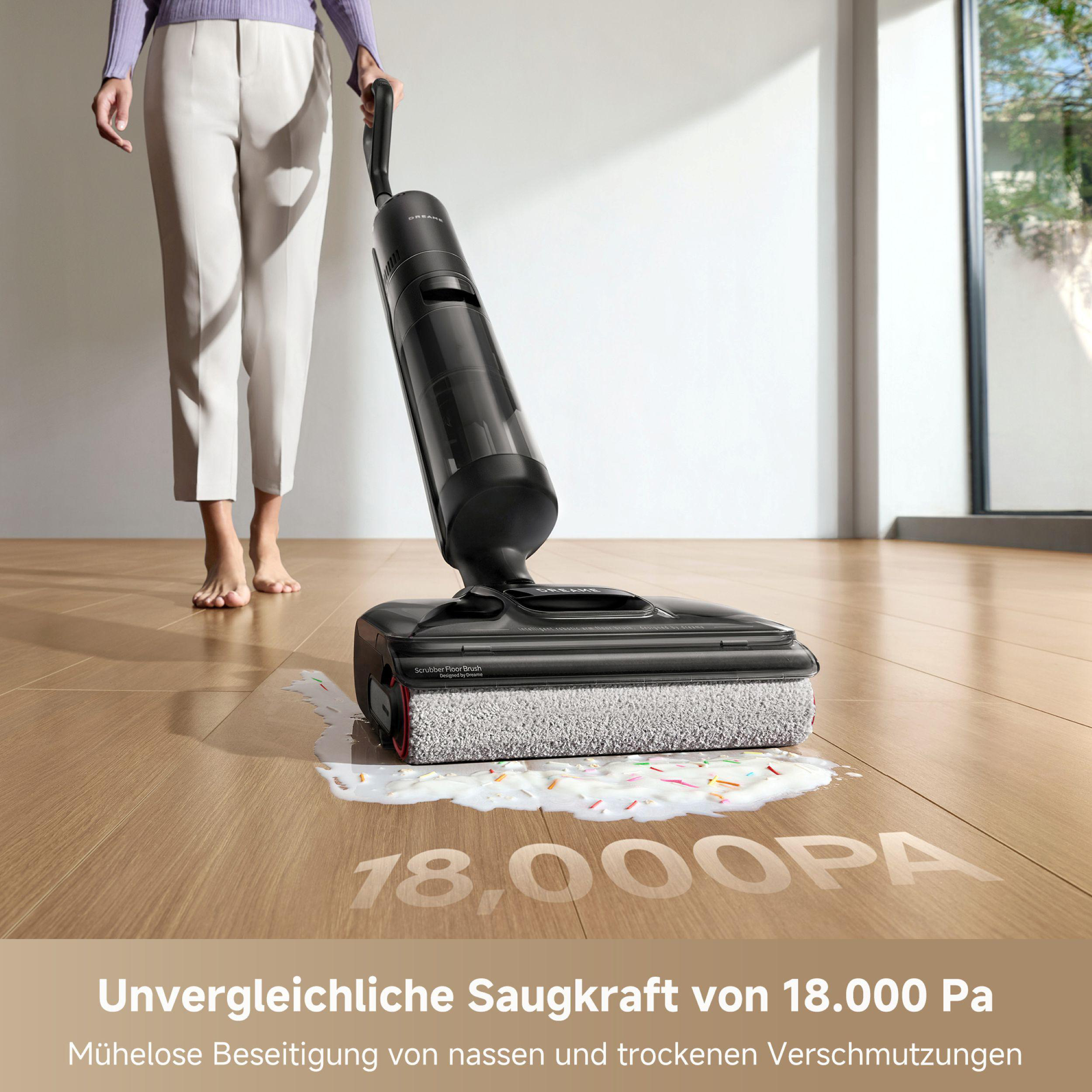 Person verwendet einen schwarzen Bodenreiniger auf Holzboden. Der Reiniger befindet sich auf einer verschütteten Flüssigkeit mit Streuseln.