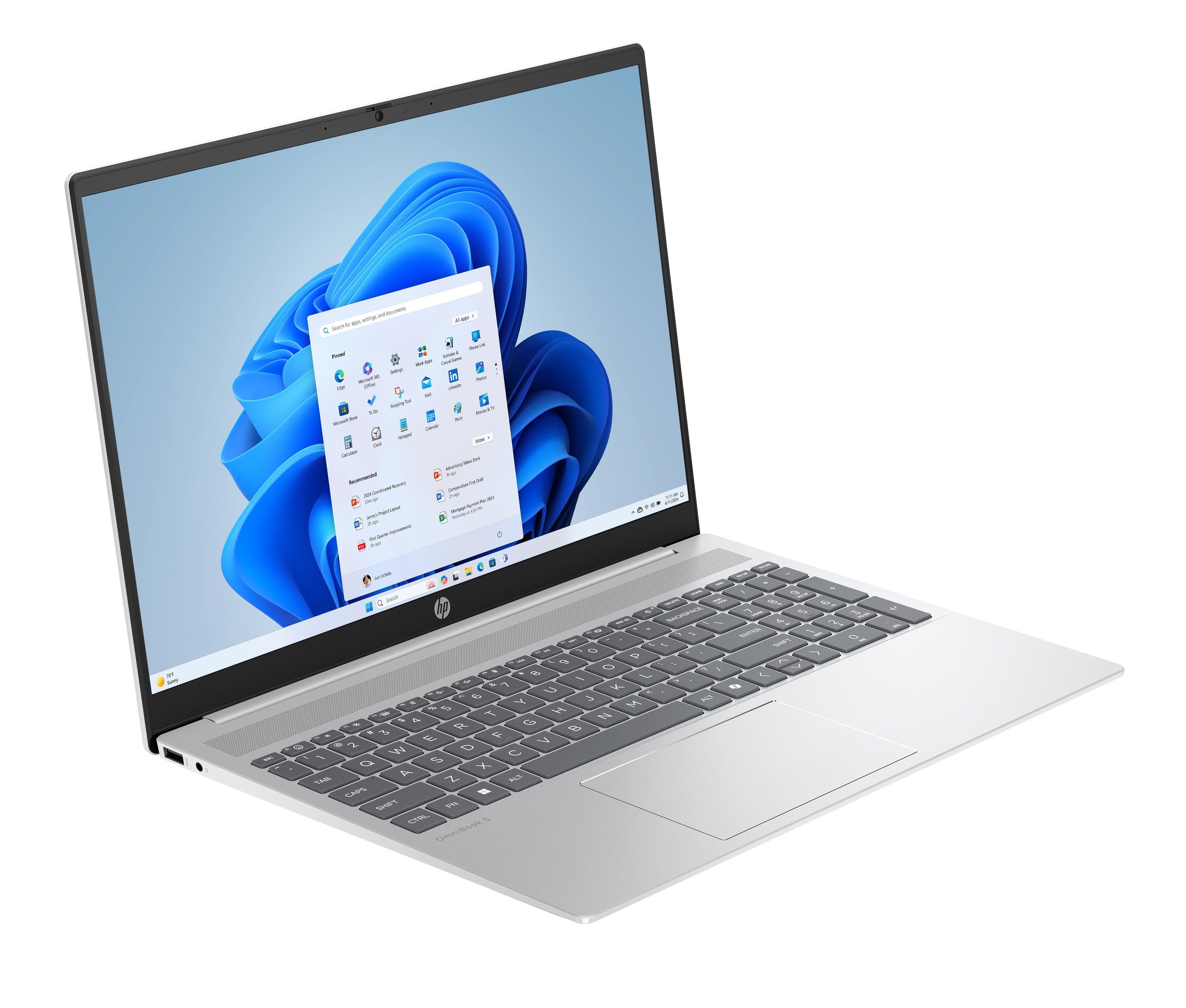Silberner Laptop mit geöffnetem Windows 11-Desktop. Der Laptop steht auf weißer Oberfläche.
