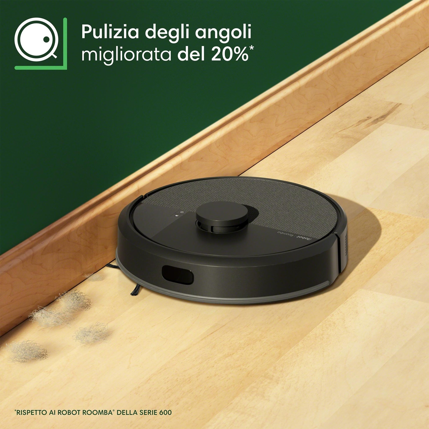 Un aspirapolvere robot nero è su un pavimento di legno ed è vicino a un muro verde.