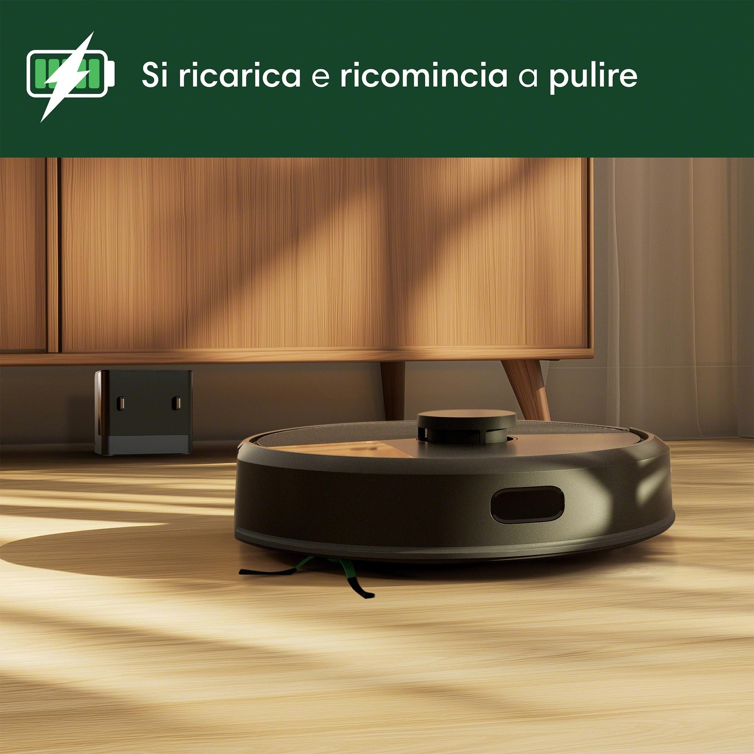 Un aspirapolvere robot nero su un pavimento in legno, vicino a mobili e una stazione di ricarica.