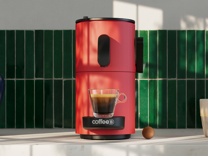 Eine rote Kaffeemaschine auf grüner Fliesenoberfläche. Eine Tasse Espresso steht auf der Basis.