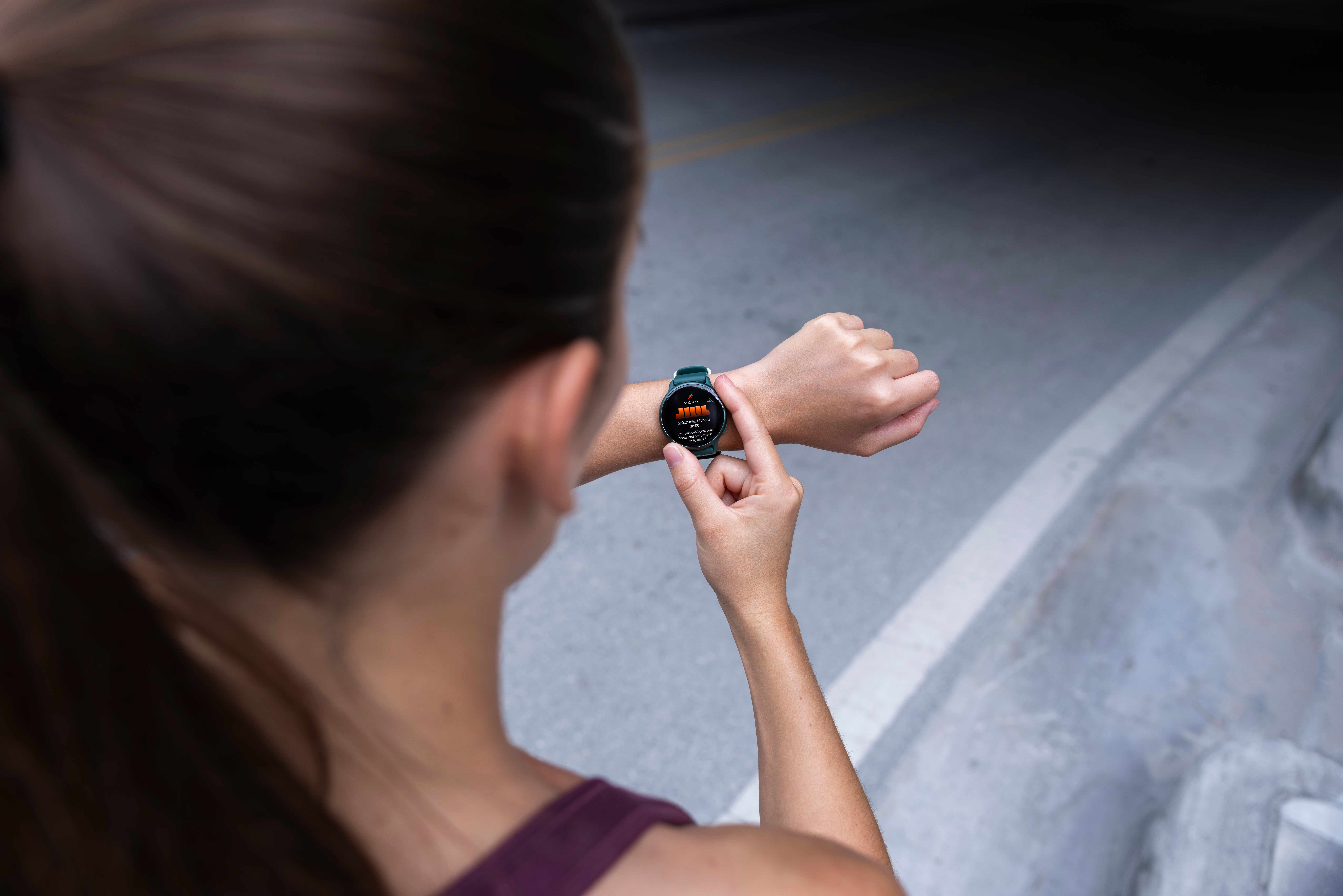 Femme portant une smartwatch, vérifiant ses données d'entraînement. La montre affiche des statistiques comme la fréquence cardiaque.