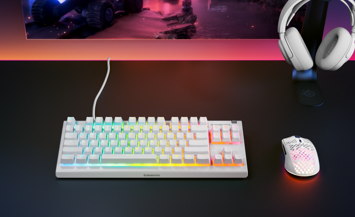 Weiße Tastatur, Maus und Kopfhörer auf schwarzem Untergrund. Regenbogenfarbene Tastatur.