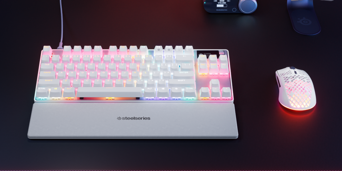 Weiße Tastatur mit farbigen Tasten und einer weißen Handgelenkauflage, neben einer weißen Maus.