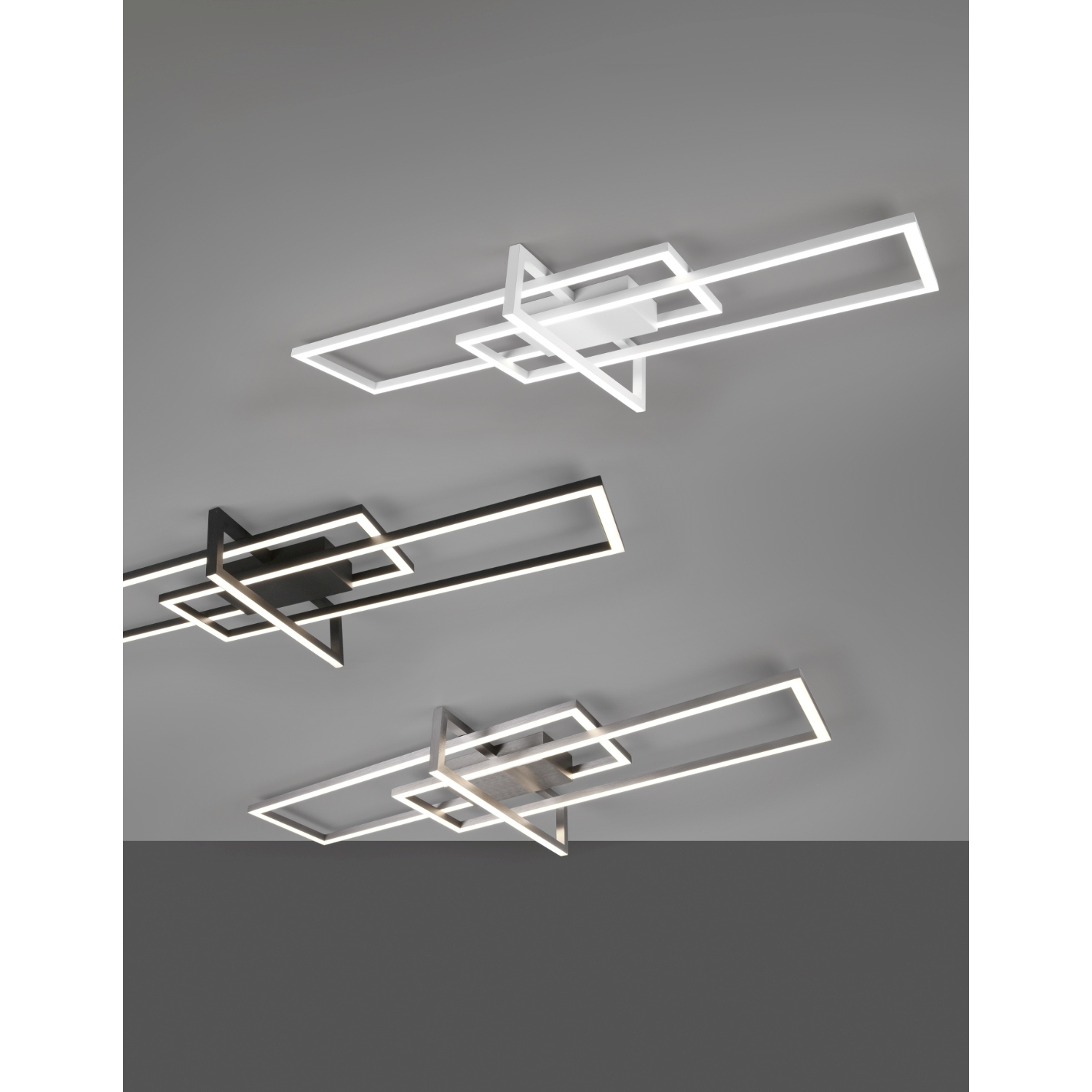 Tre lampade da soffitto con forme geometriche. Una bianca, una nera e una argentata.