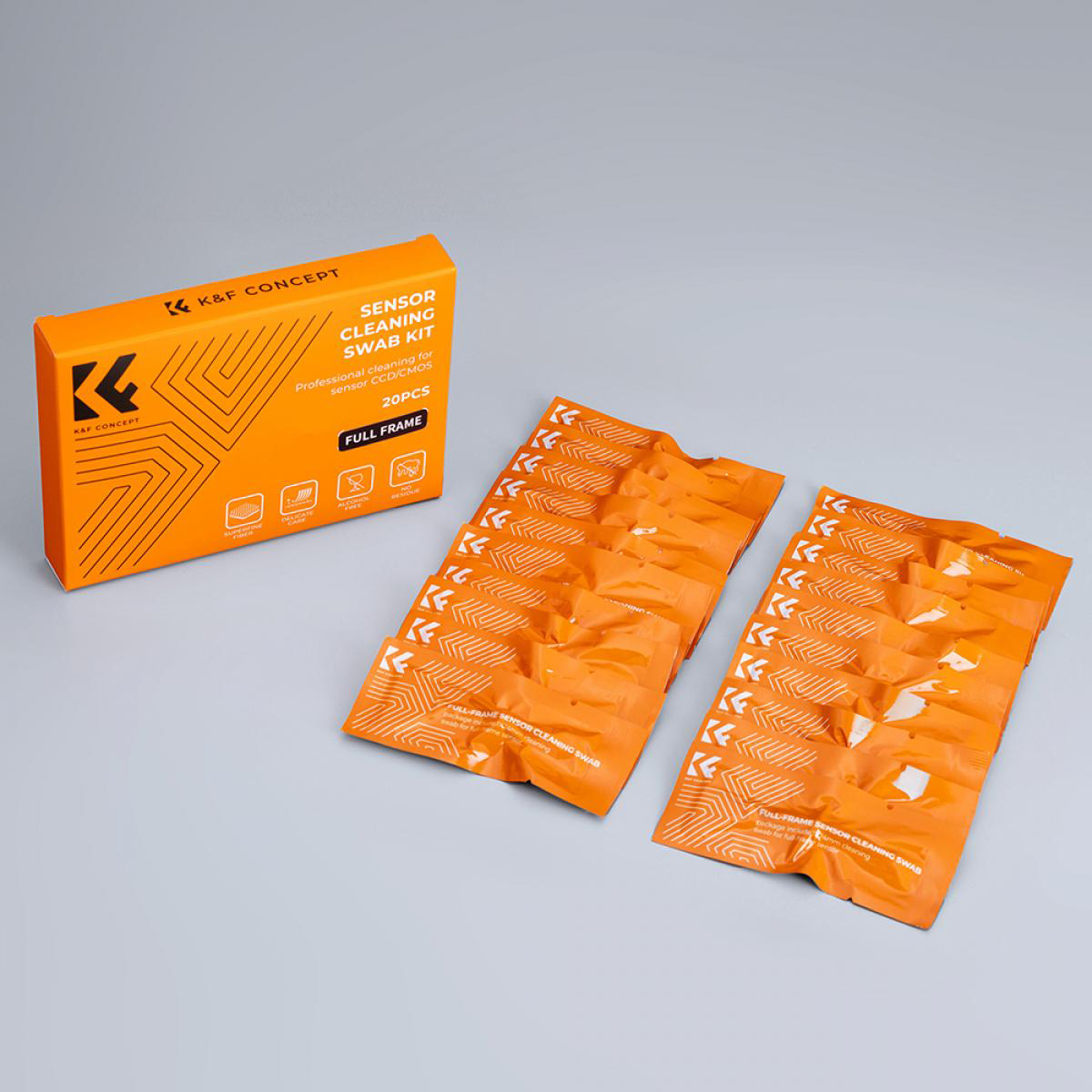 Narancssárga doboz 'Sensor Cleaning Swab Kit' felirattal és tisztító pálcák csomagjai szürke felületen.