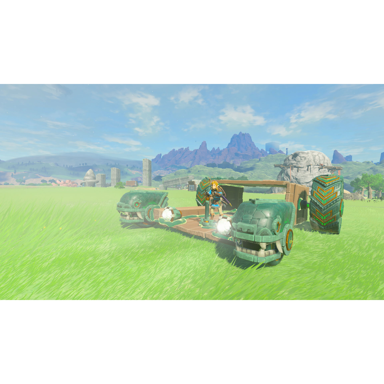 A character drives a vehicle in a green field, mountains in the background.