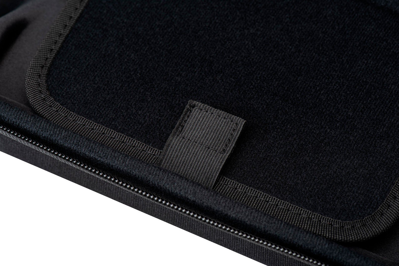 Zbliżenie wnętrza czarnej obudowy z paskiem na rzep i szwem z białymi przeszyciami.