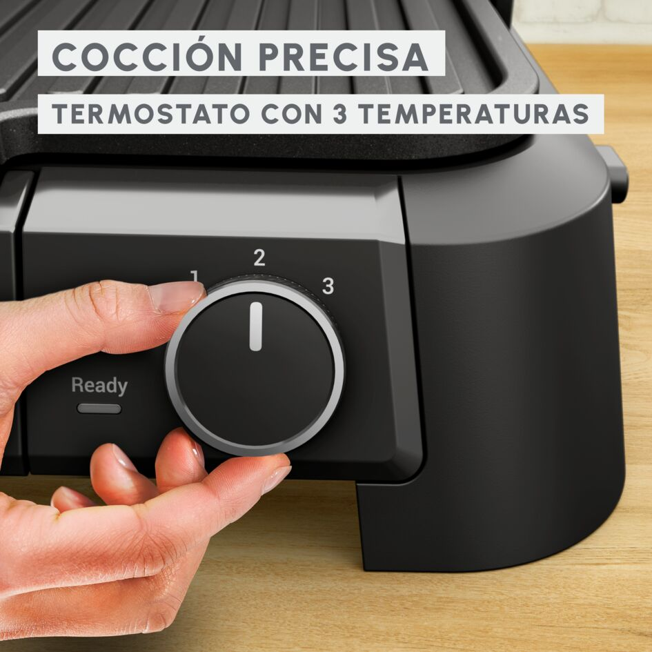 Mano girando un dial en una parrilla negra. Texto: Cocción precisa, termostato con 3 temperaturas.