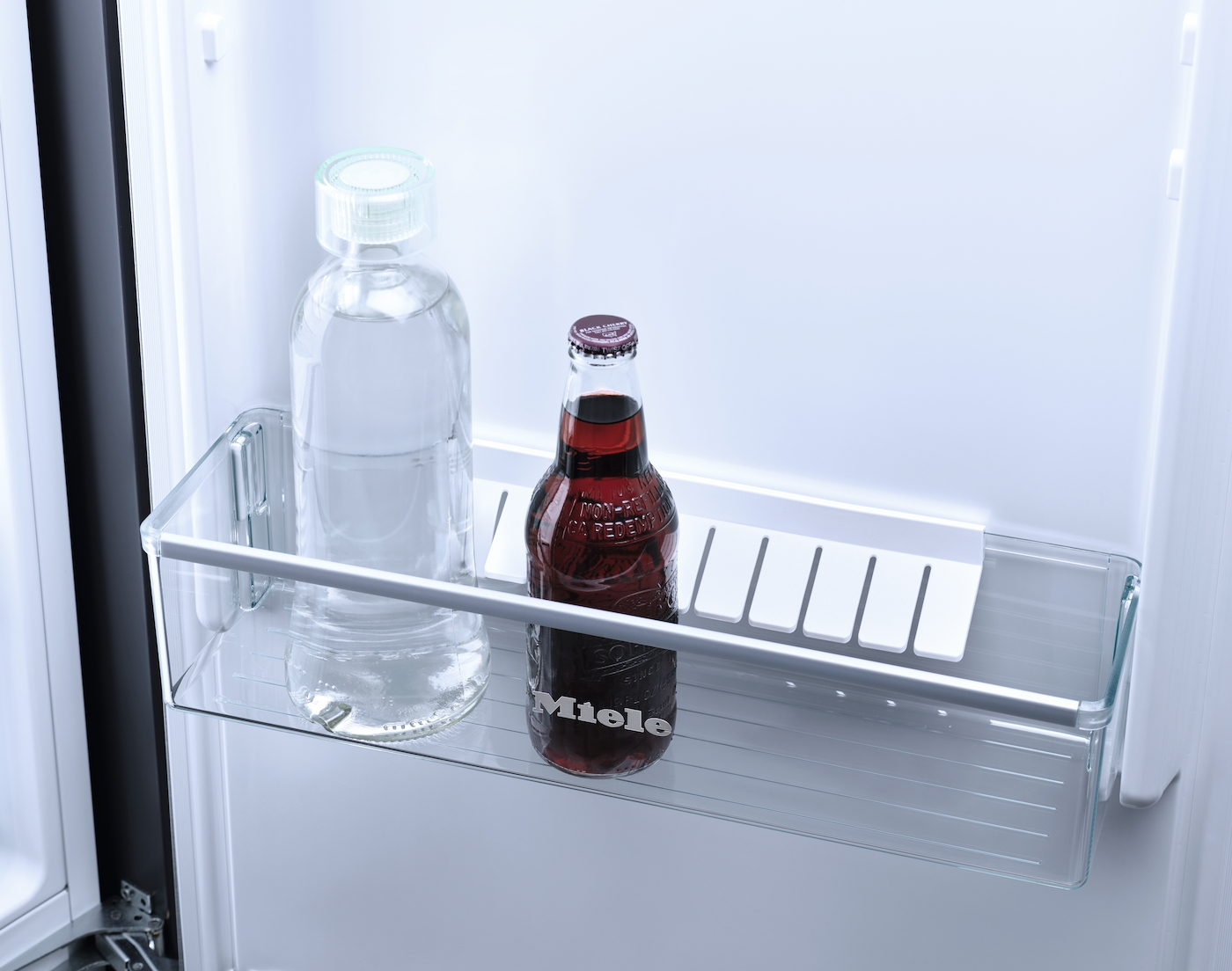 Kühlschrankregal mit einer Wasserflasche und einer Flasche roter Limonade.