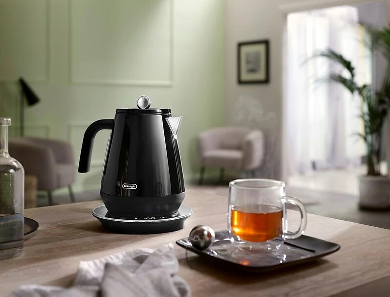 Czarny czajnik elektryczny na czarnej podstawie z herbatą.