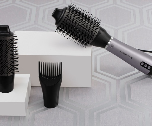 Szczotka do stylizacji włosów, grzebień i głowica szczotki znajdują się na białej powierzchni.