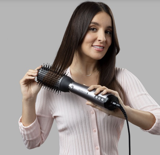 Kobieta kręci włosy za pomocą prostownicy Remington.