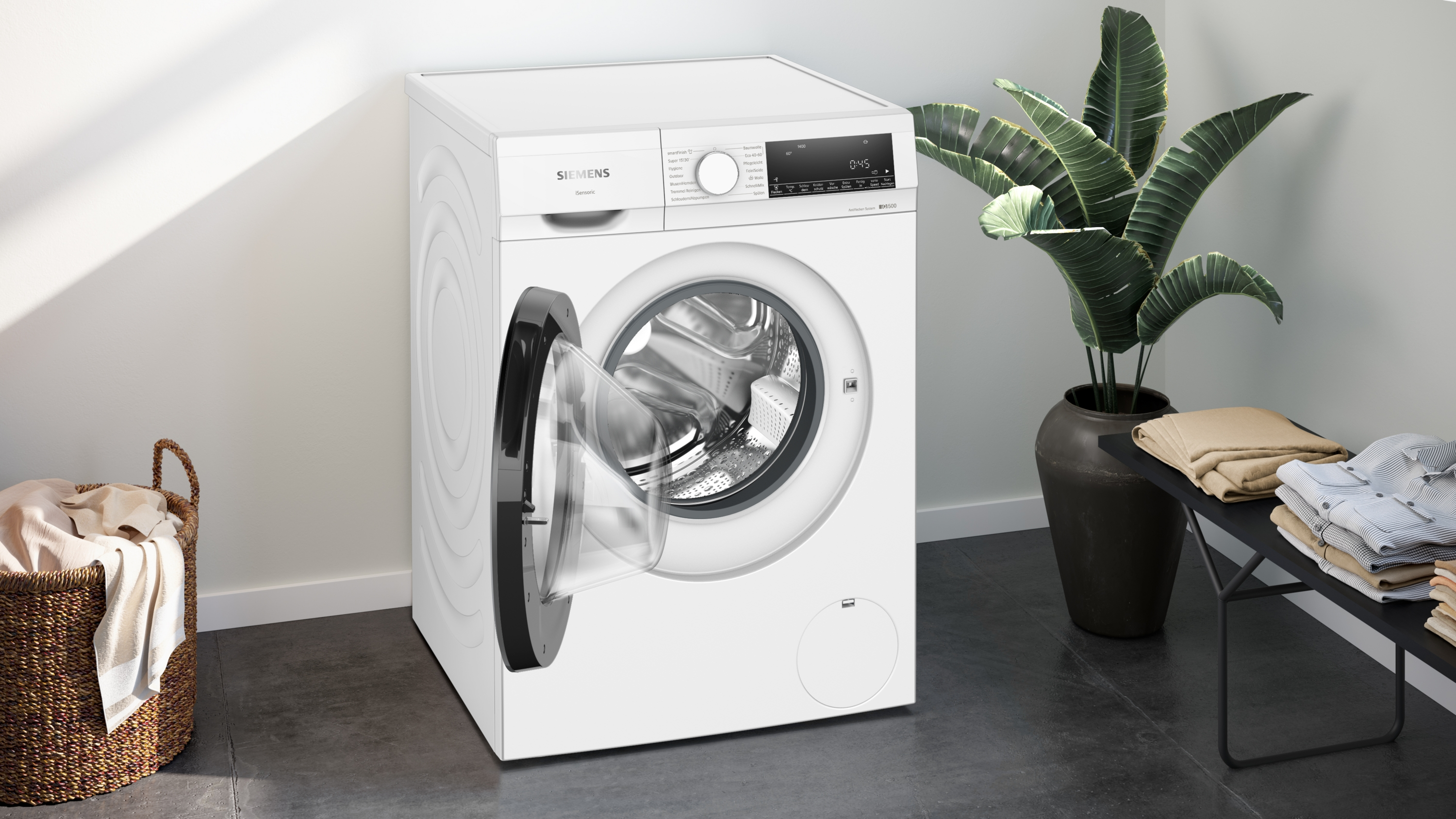 Eine weiße Waschmaschine mit geöffneter Tür und Wäschekorb.